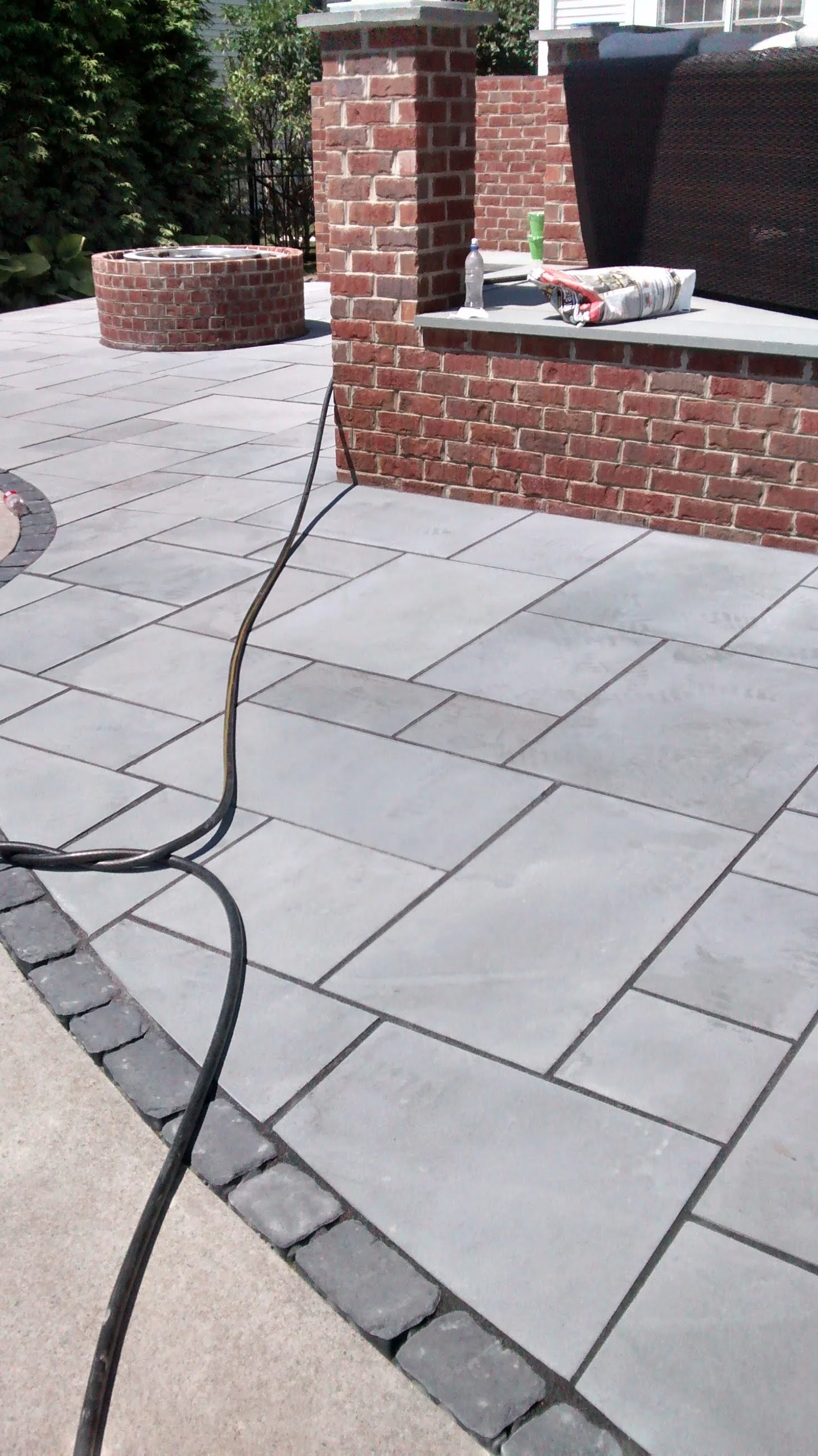 A grey banas stone paver patio with a dark border around a pool