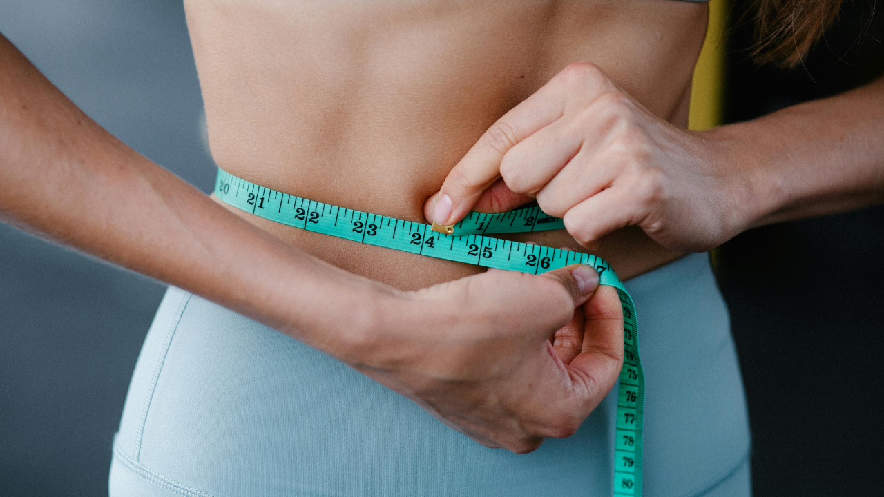 Woman holding a measuring tape around her waist.