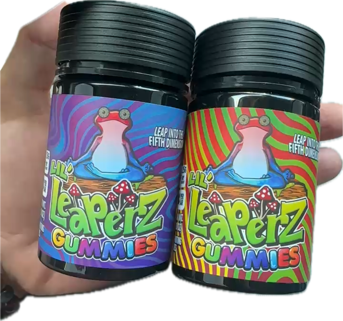 Two bottles of Leaperz Gummies featuring colorful, psychedelic labels with cartoon frogs in meditative poses. One bottle has a purple and blue background, the other has a red and green background. Both bottles are held in someone's hand.