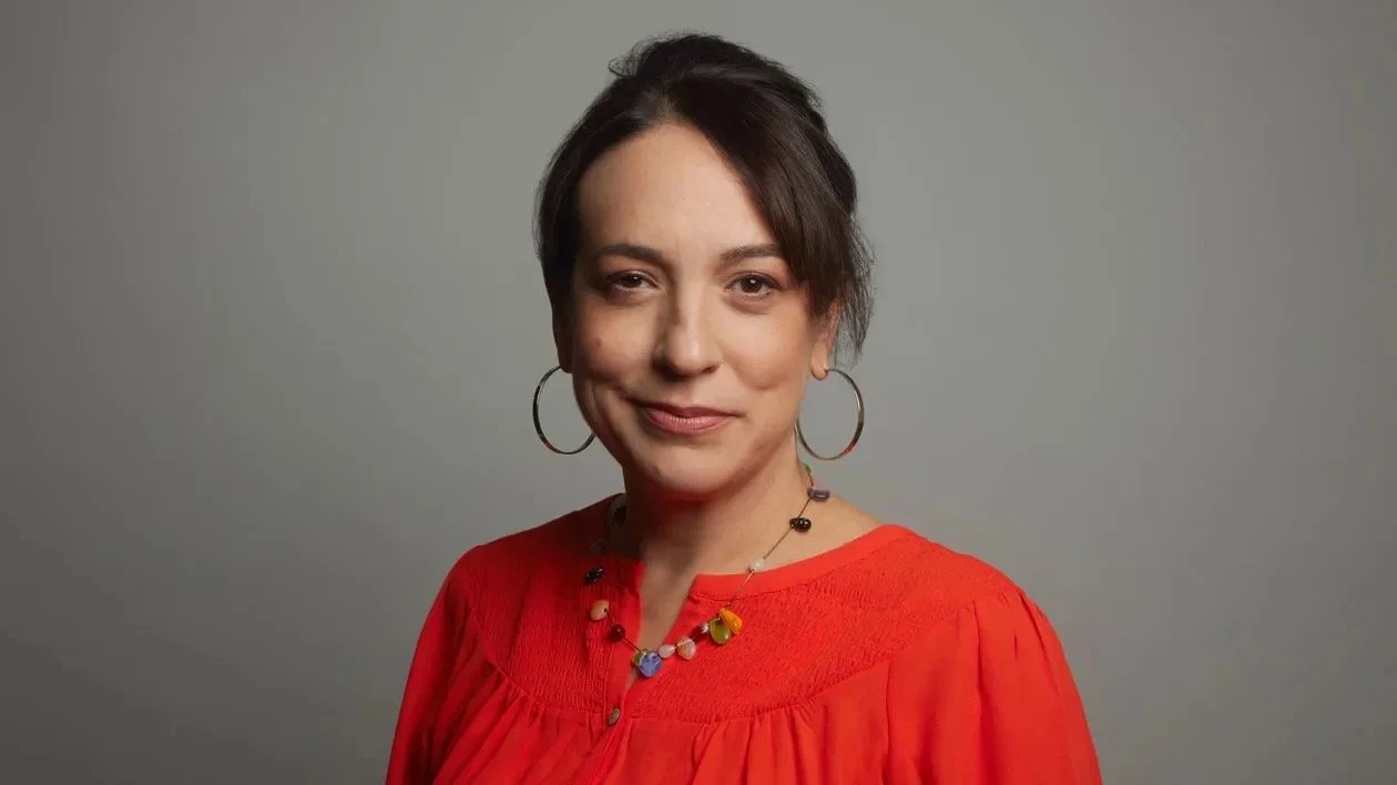 Woman wearing a red top and hoop earrings