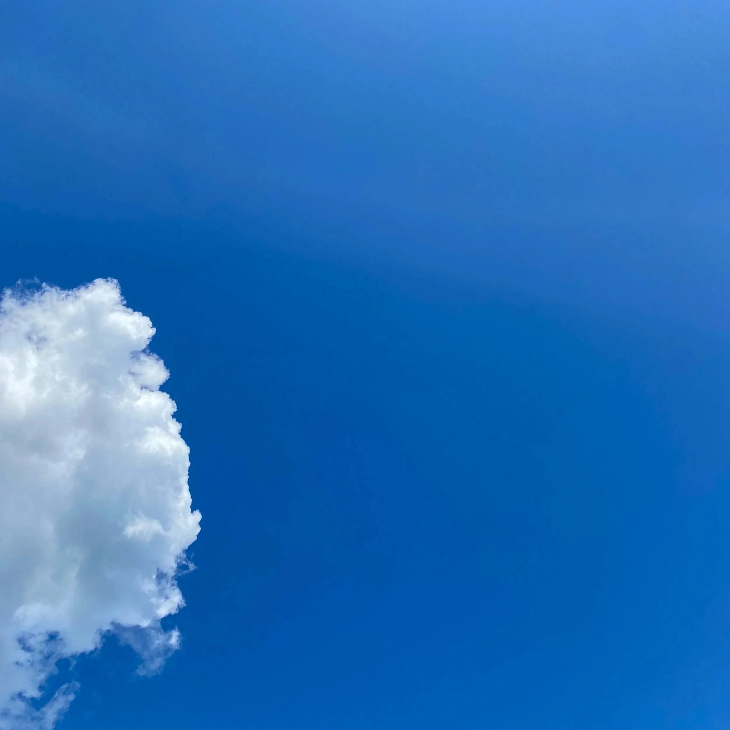 Whistler BC, Summertime. A partly cloudy sky with a large white cloud on the left side against a blue sky.