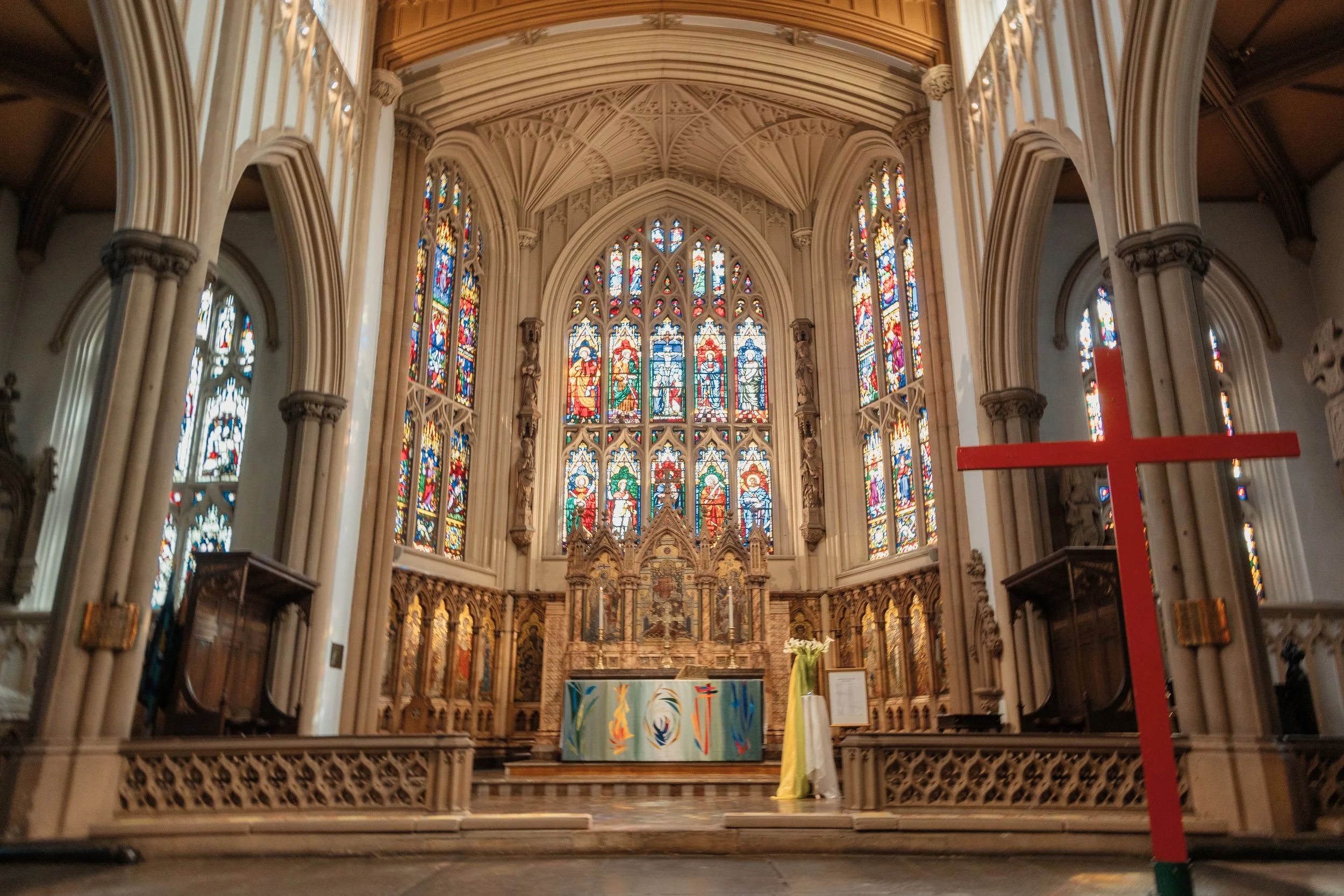 interior of leeds minster with red wooden cross and stained glass windows