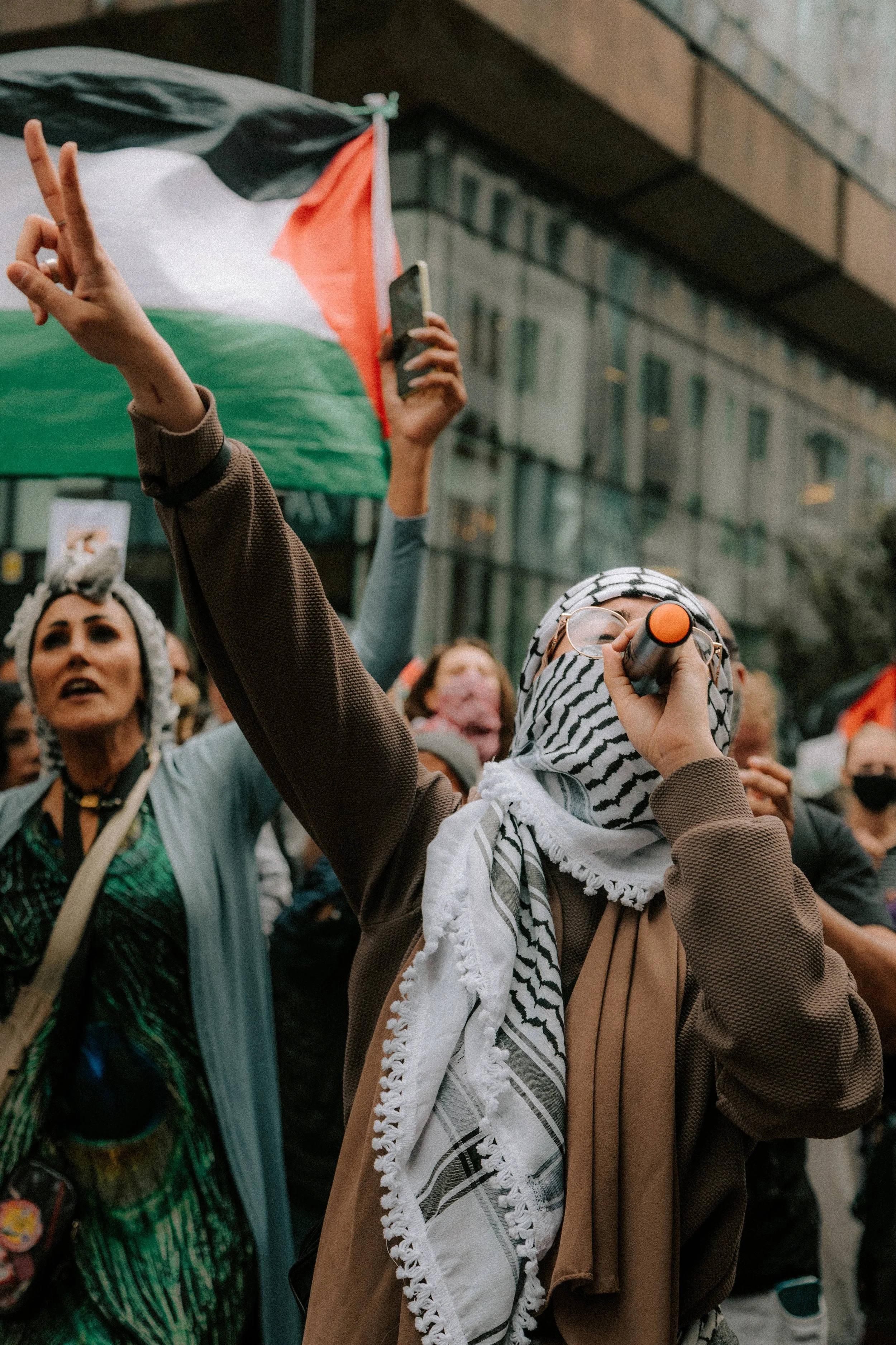 woman in keffiyeh holding peace sign at Palestine protest in Leeds