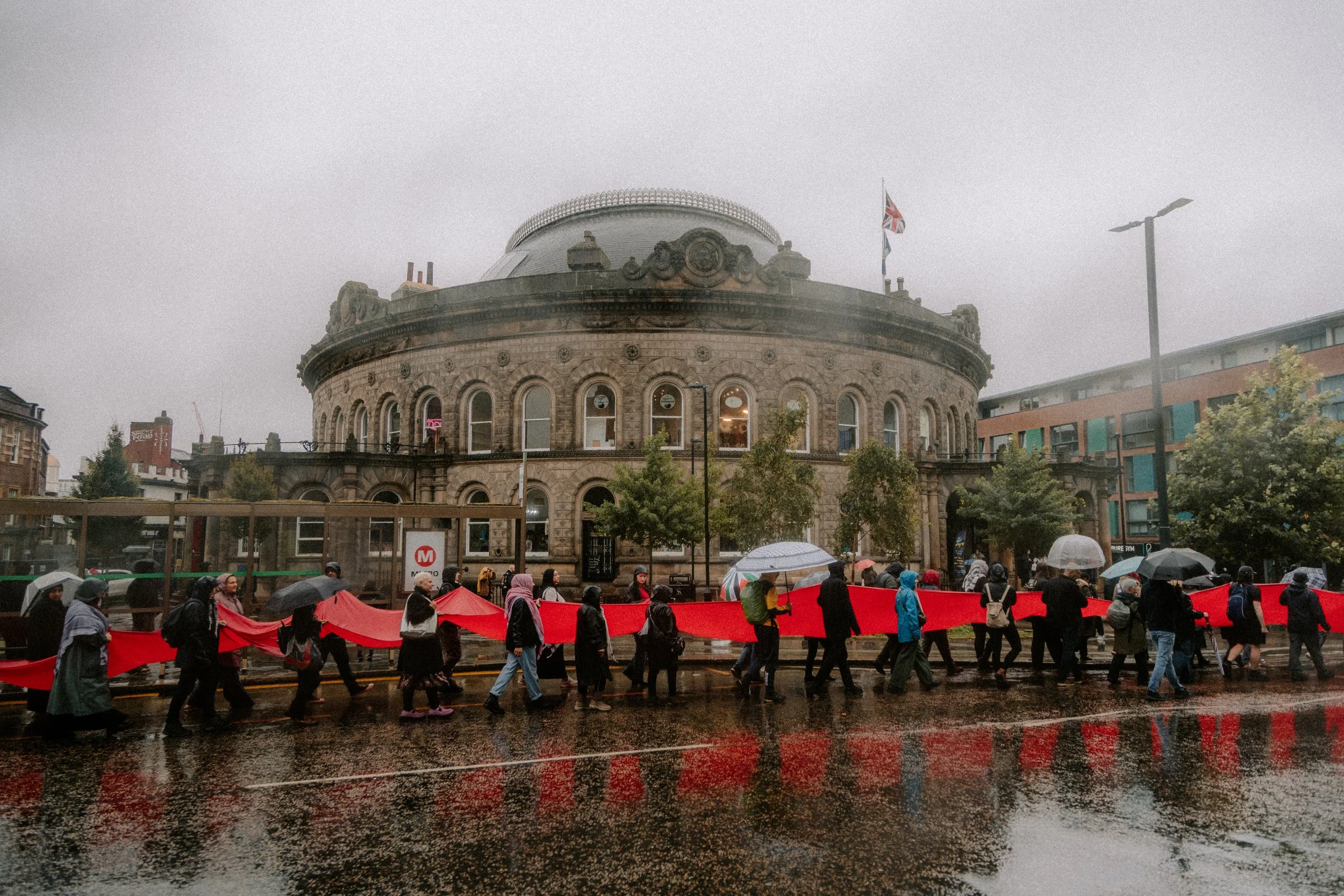 Palestine protest holding red fabric in Leeds City Centre outside the corn exchange