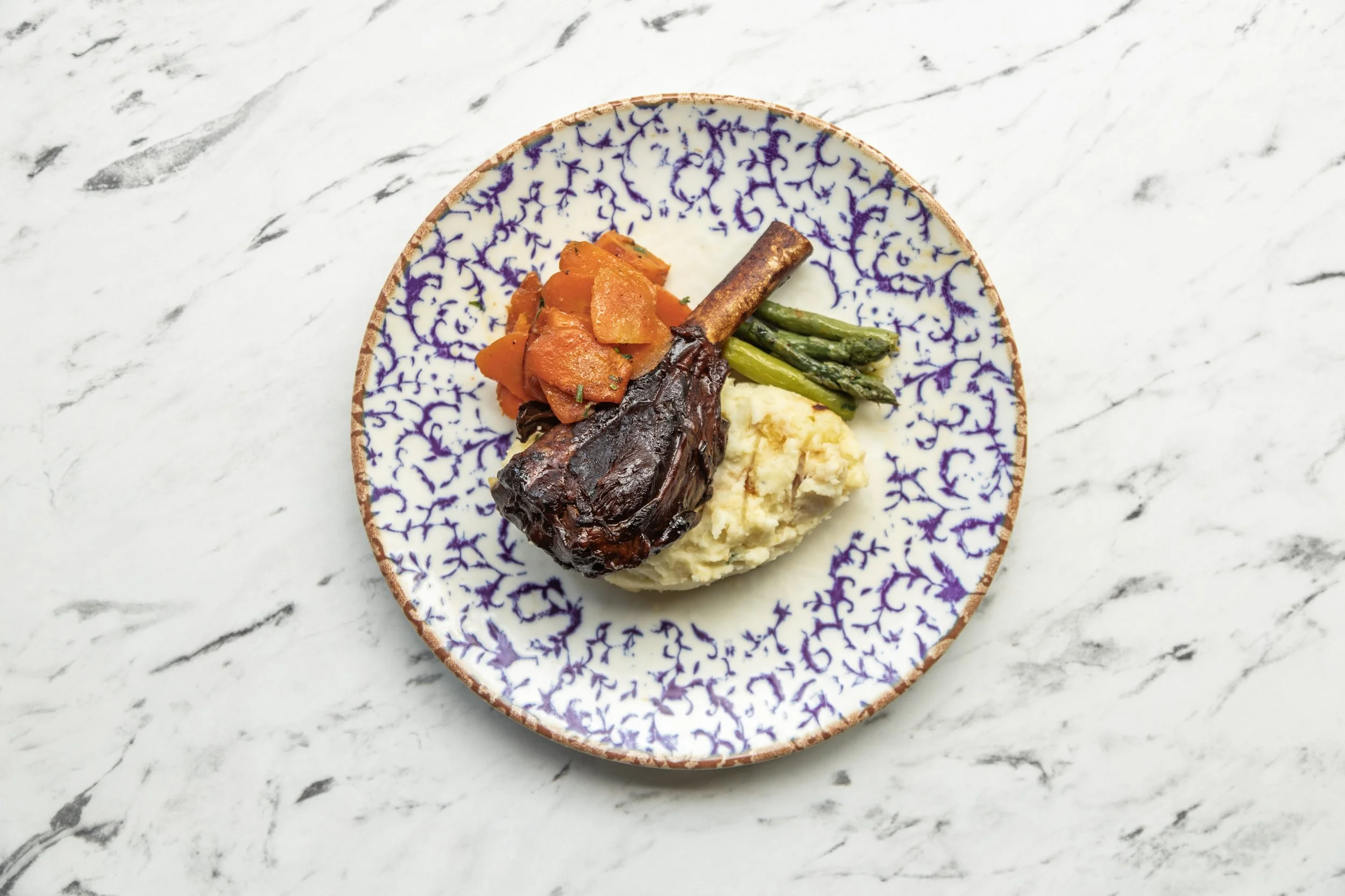Plate with cooked carrots, green beans, mashed potatoes, and a glazed beef short rib on a white marble countertop. york leeds yorkshire restaurant photographer videographer