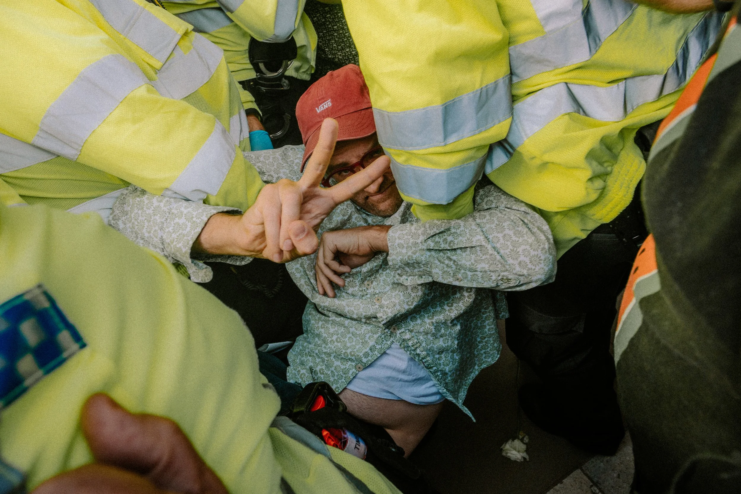 Man holds peace sign while being carried by police. Taken at a Defend Our Juries protest against the proscription of Palestine Action which took place in Parliament Square on the 6th September 2025. Over 1000 people were arrested holding signs. 