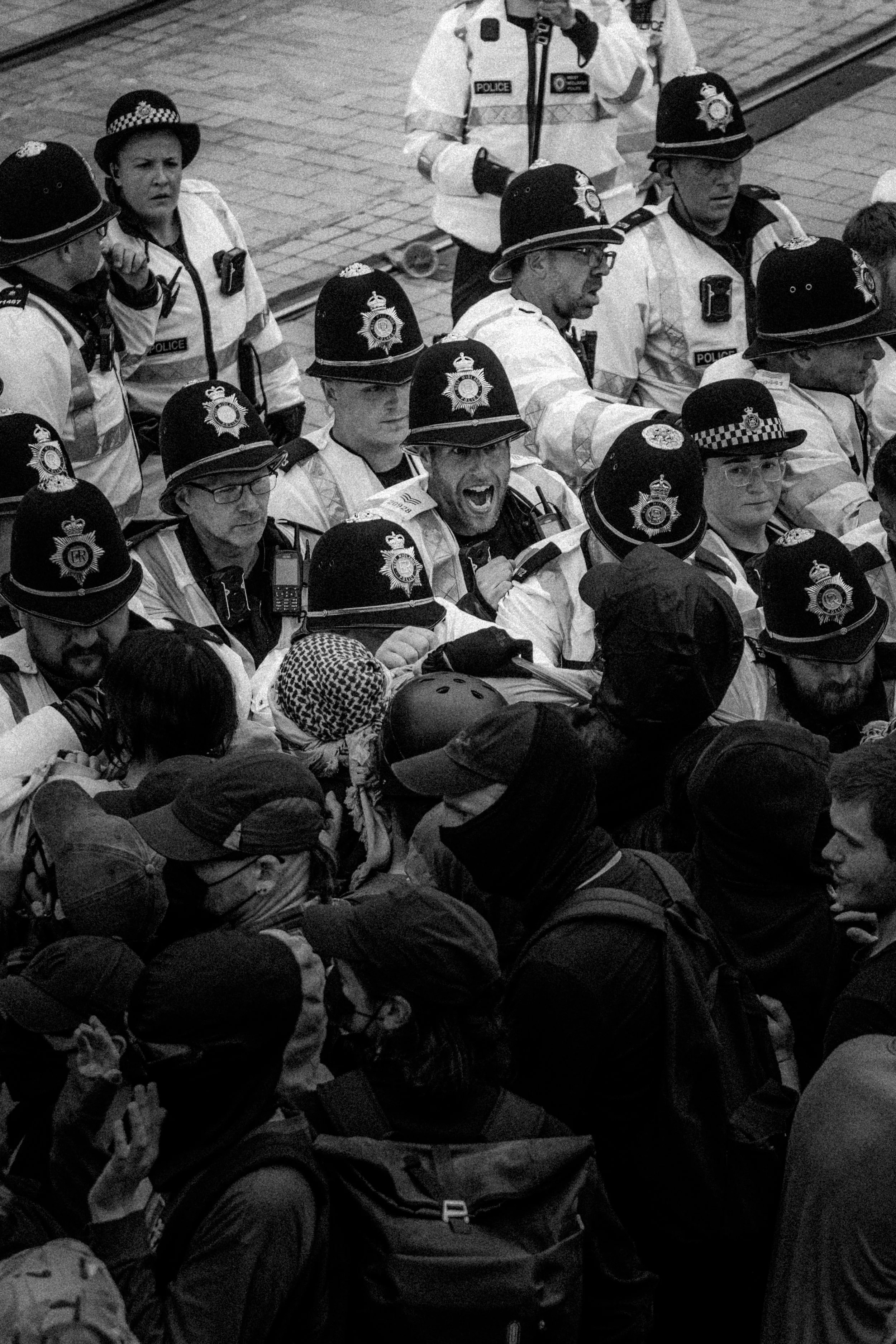 Group of police officers in uniform push anti-fascist protesters
