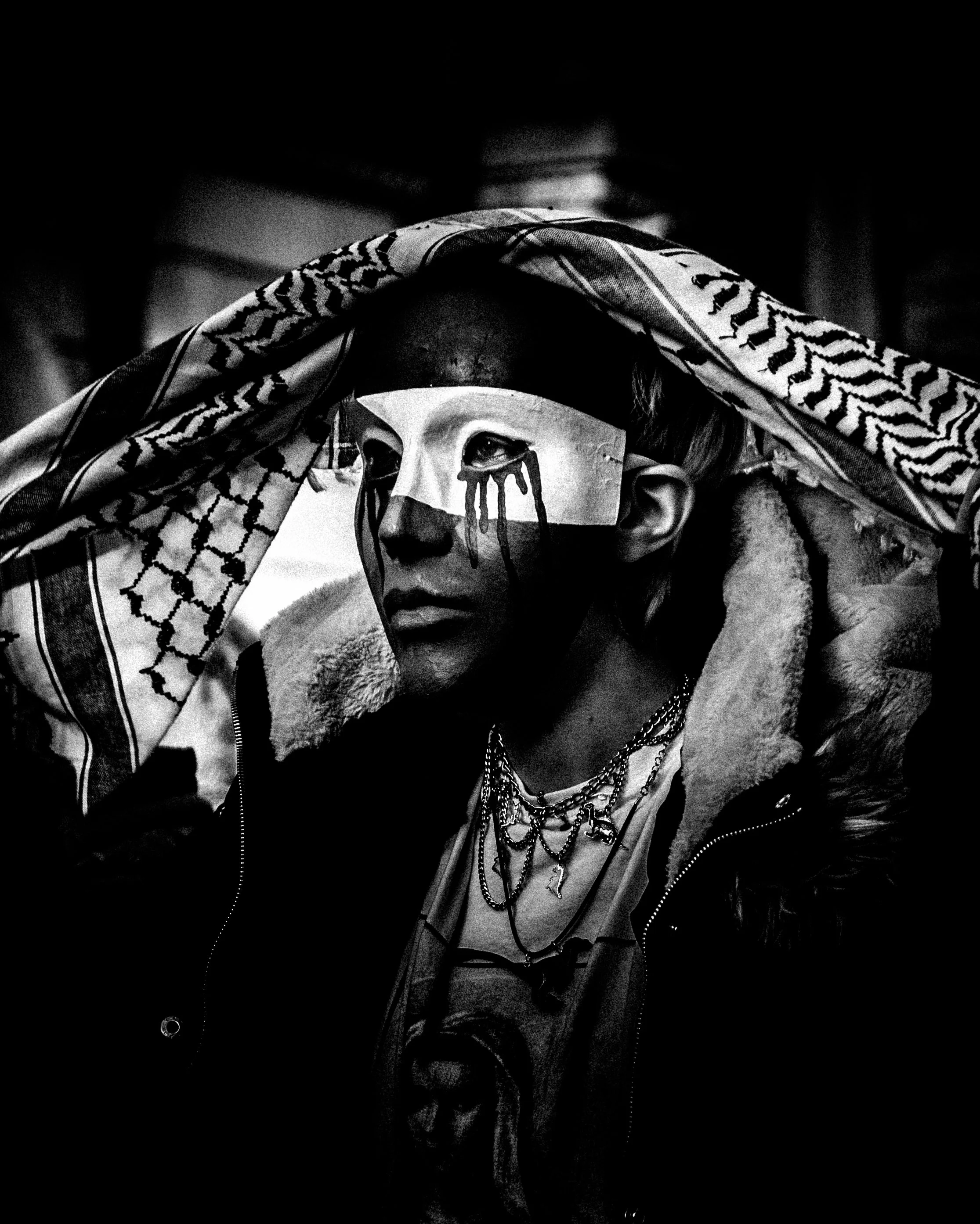 Protester in a Palestine mask holds a keffiyeh over their head