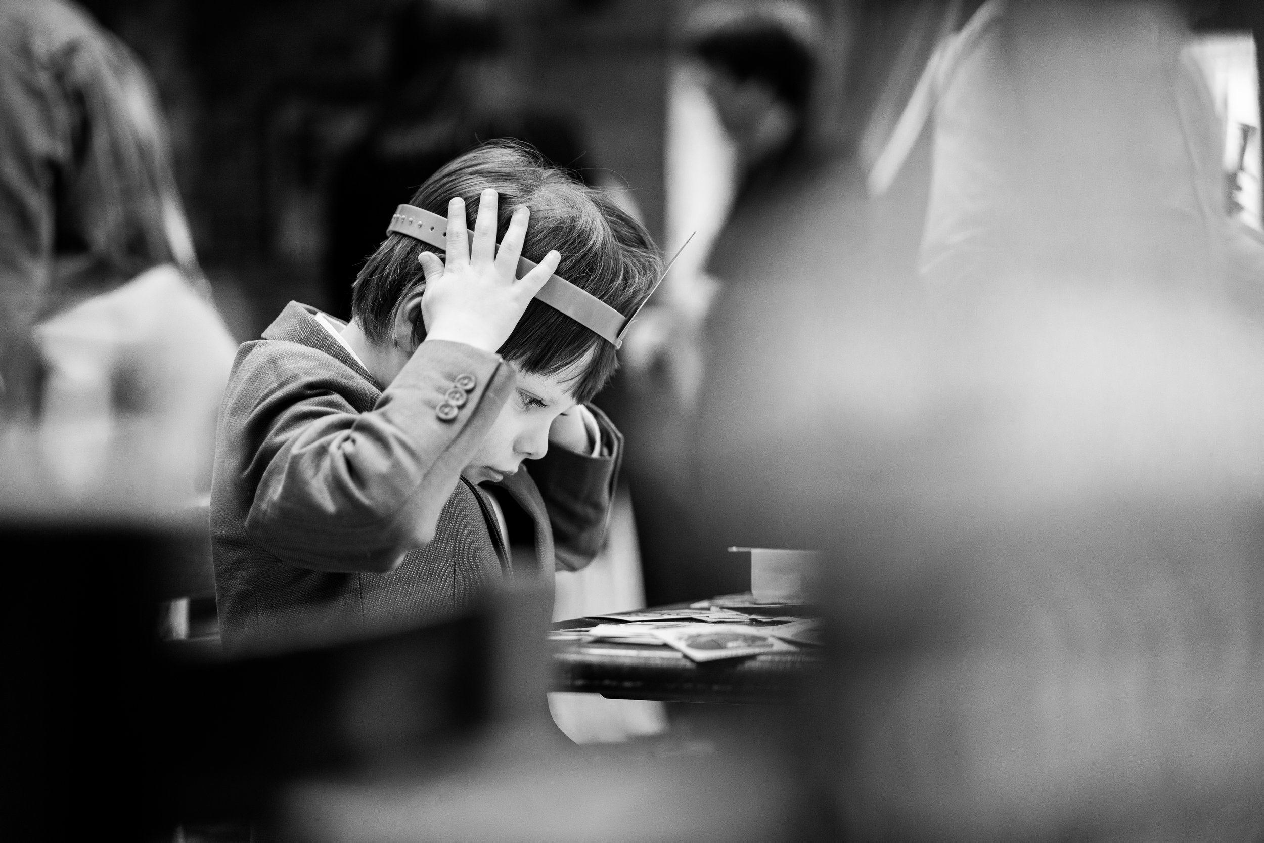 Black and white photo of a child wearing a headband, sitting at a table with cards, appearing focused and contemplative.