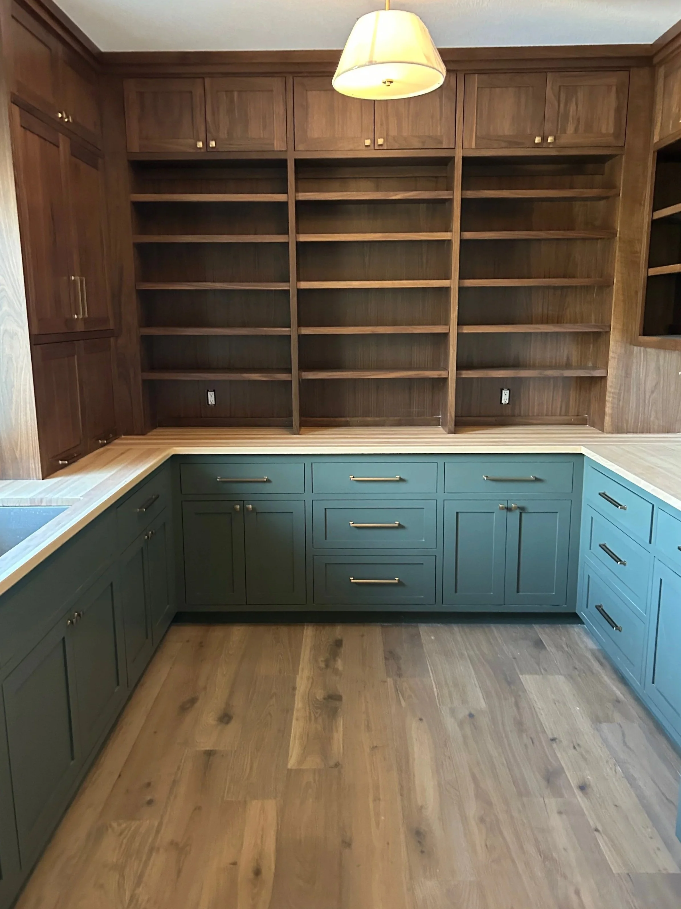 Empty kitchen with wooden cabinets, blue lower cabinets, open shelving, and hardwood floor.