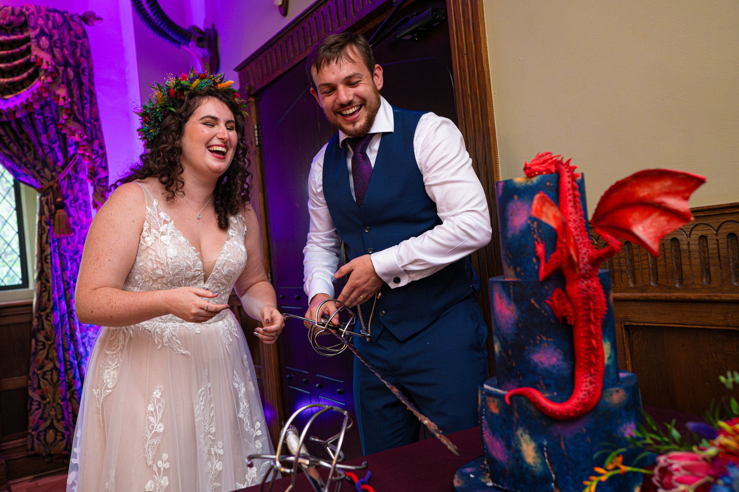 summer bride and groom doing their cake cut - wedding cake with Welsh Red Dragon - wedding cake cutting photography with swords