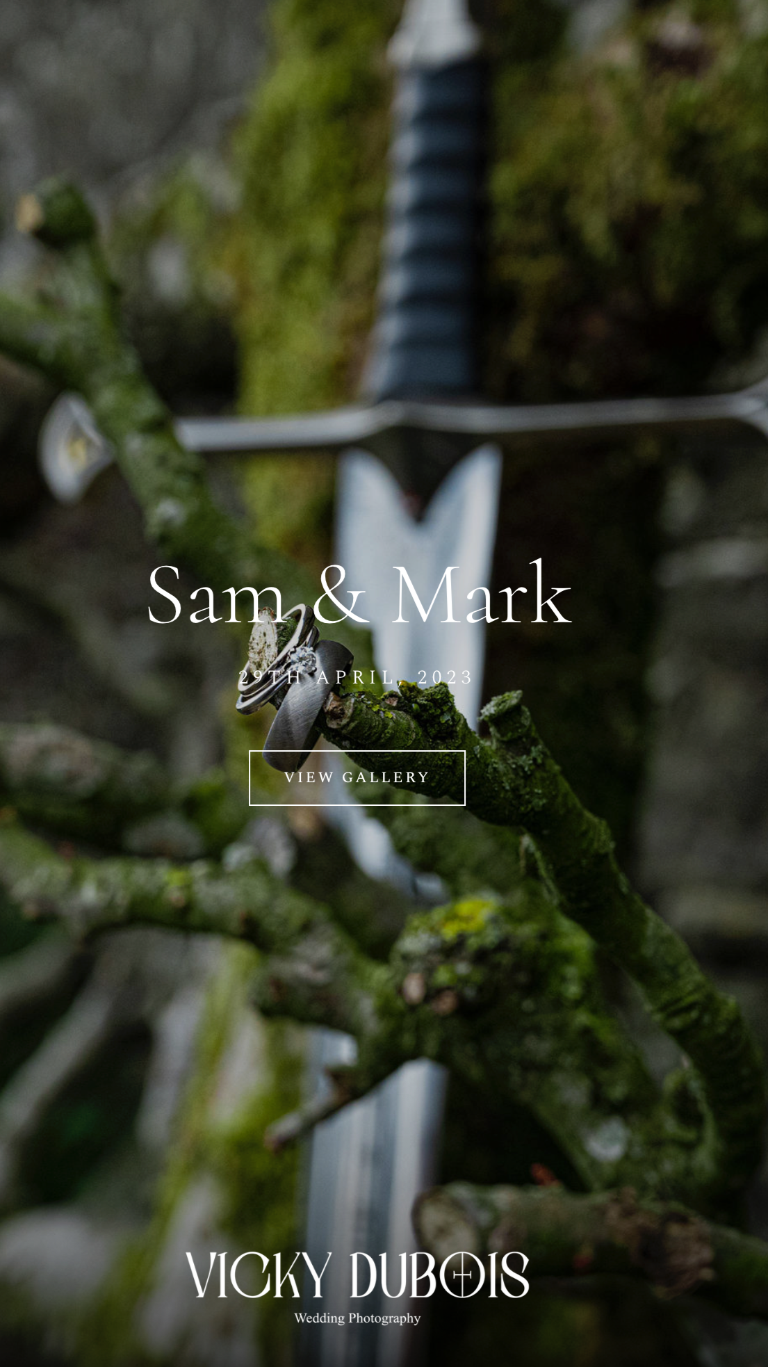 Close-up of wedding rings resting on a moss-covered tree branch with a blurred garden background, with text overlay promoting a wedding photography gallery by Vicky Dubois