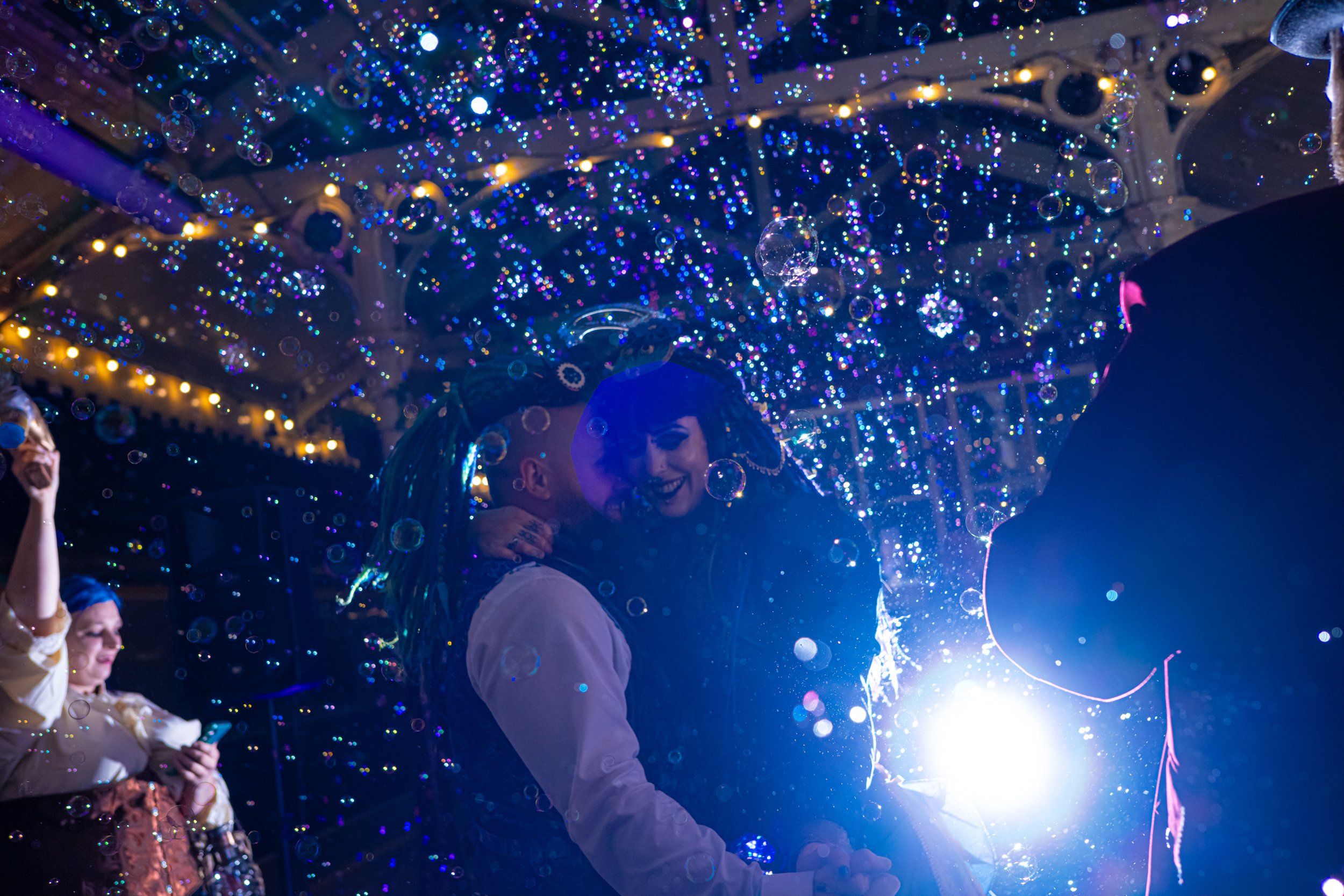 neon steampunk wedding on a vintage railway - colourful wedding photos with bubbles during their first dance photography - bride in victorian wedding dress and dreadlocks - groom with green mattocks