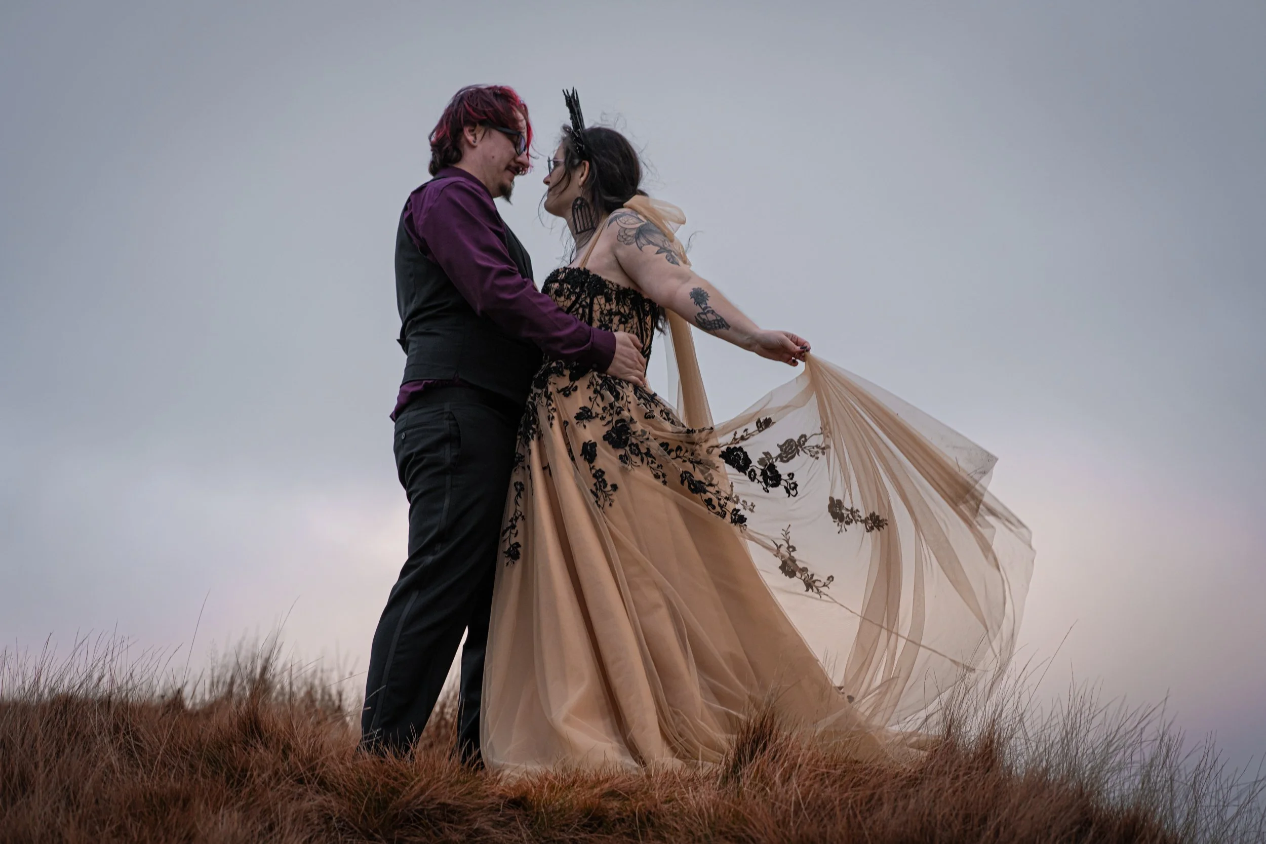 Alternative couple standing on a hill at the Pendle moors. Post wedding shoot for their first anniversary.