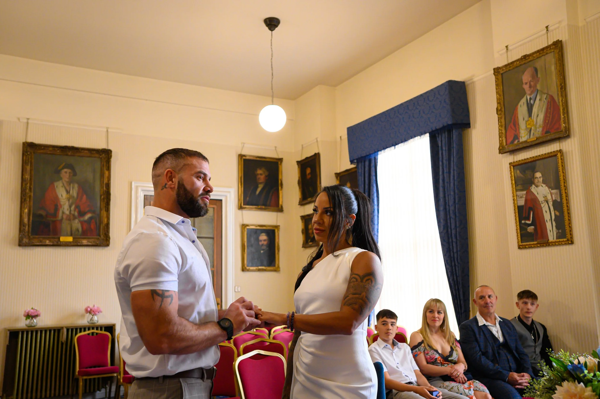 Intimate wedding ceremony at Leeds town hall. Mixed are Jamaican bride looks longingly at her husband to be. Simple off the shoulder wedding dress. Elopement wedding with 5 guests.