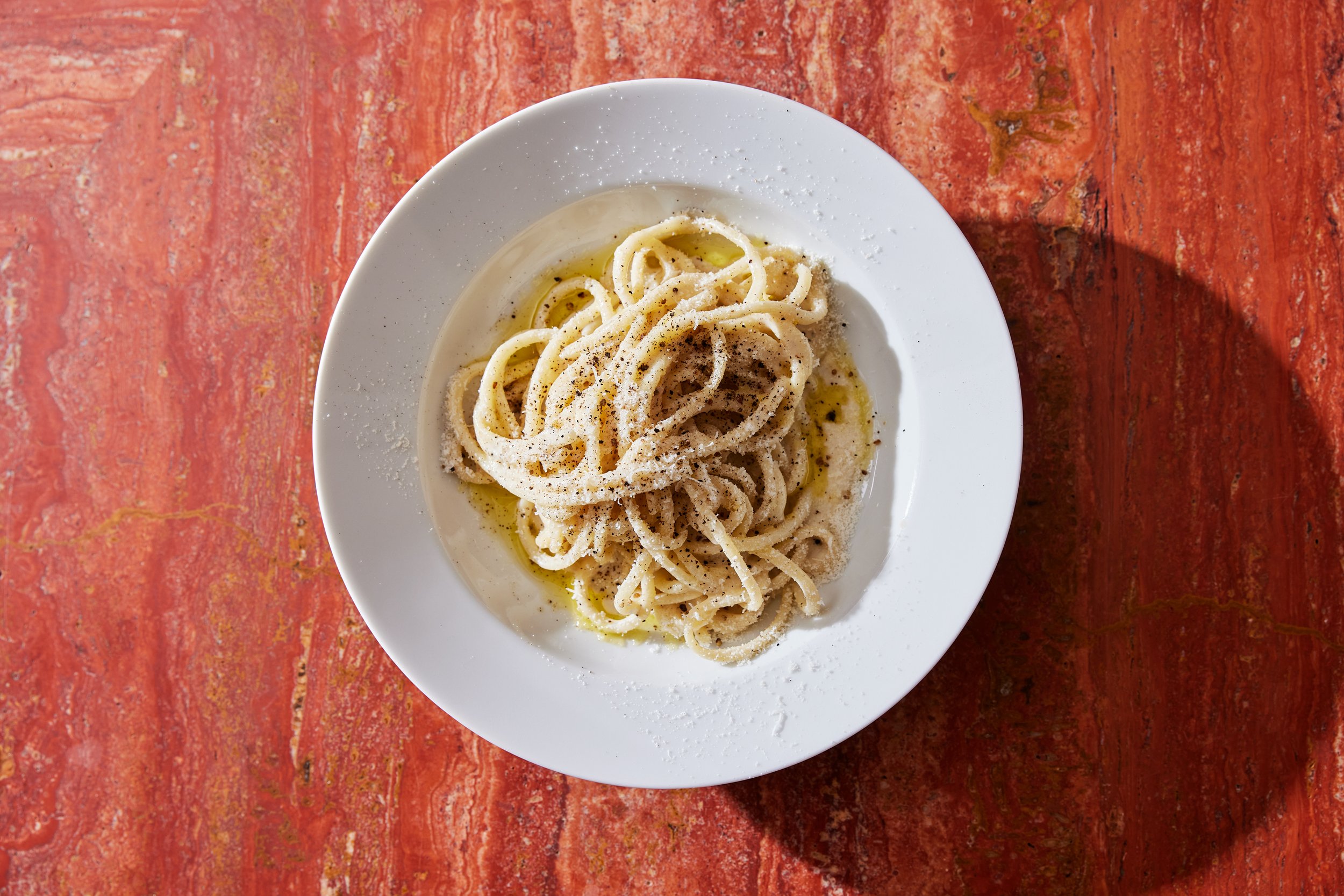 A bowl of spaghetti with cacio e pepe sits on top of a marble bar at Jupiter Restaurant. 