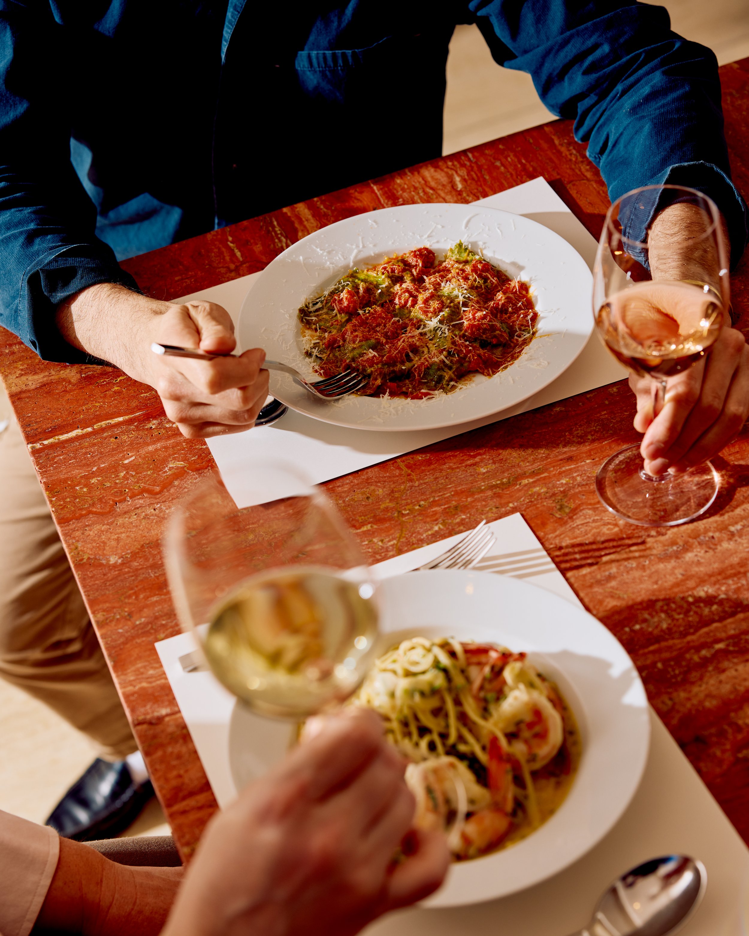Two guests enjoy pasta and wine at Jupiter Restaurant in Midtown, Manhattan for their pasta happy hour special.