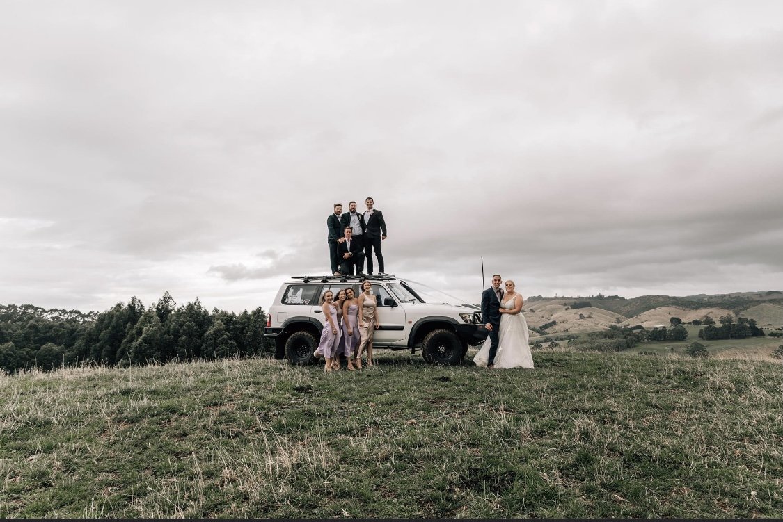 A wedding party in Gippsland standing on and around a jeep