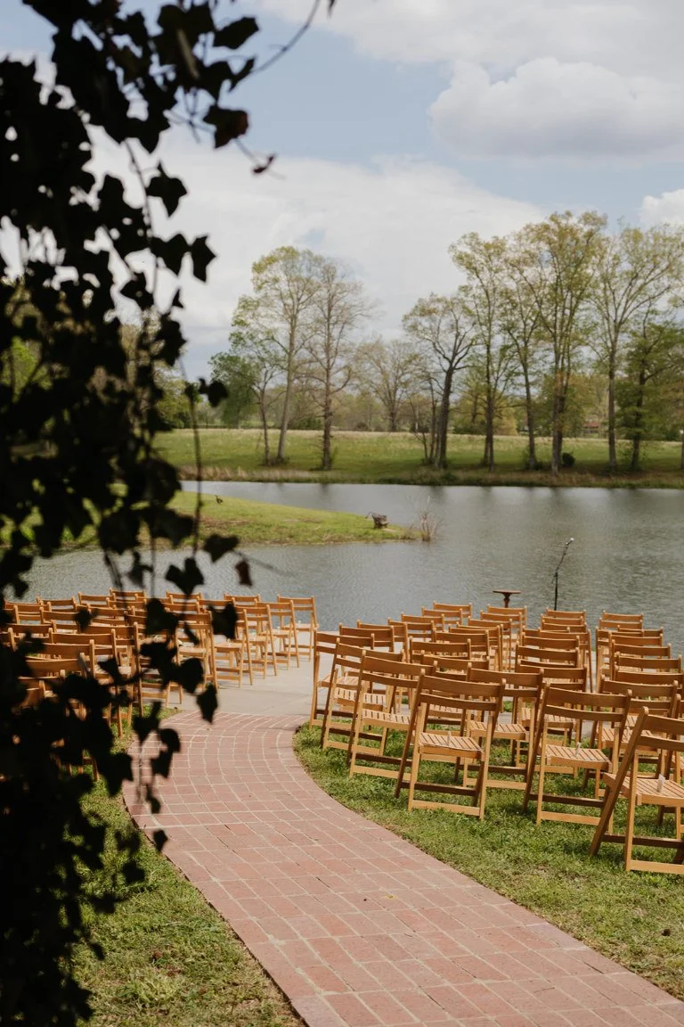 Lakeside wedding ceremony aisle with wooden chairs and a view of the water at The Eden Estate in Ashland City, Tennessee.