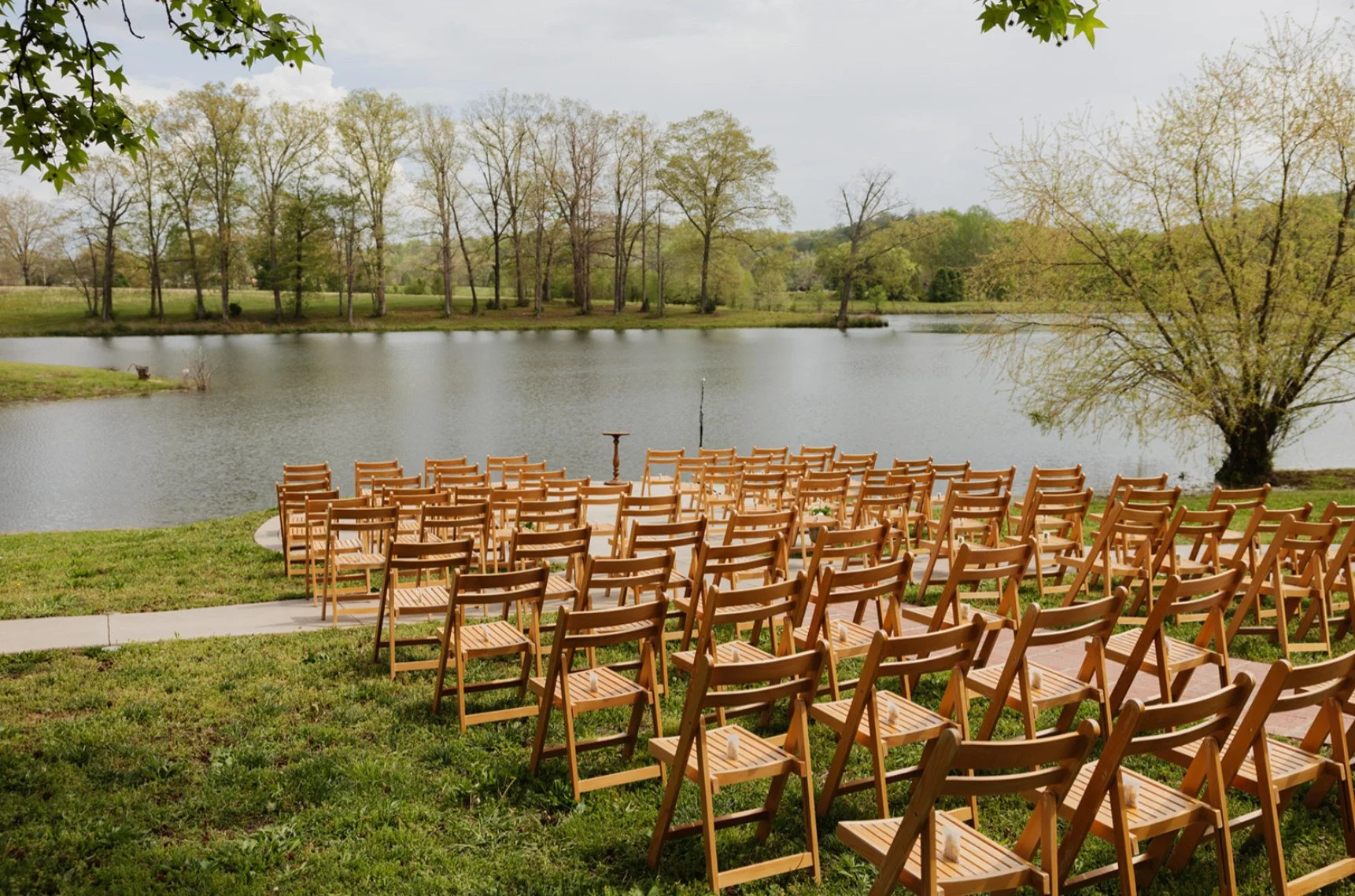 Rows of wooden chairs arranged for a lakeside wedding ceremony at The Eden Estate.