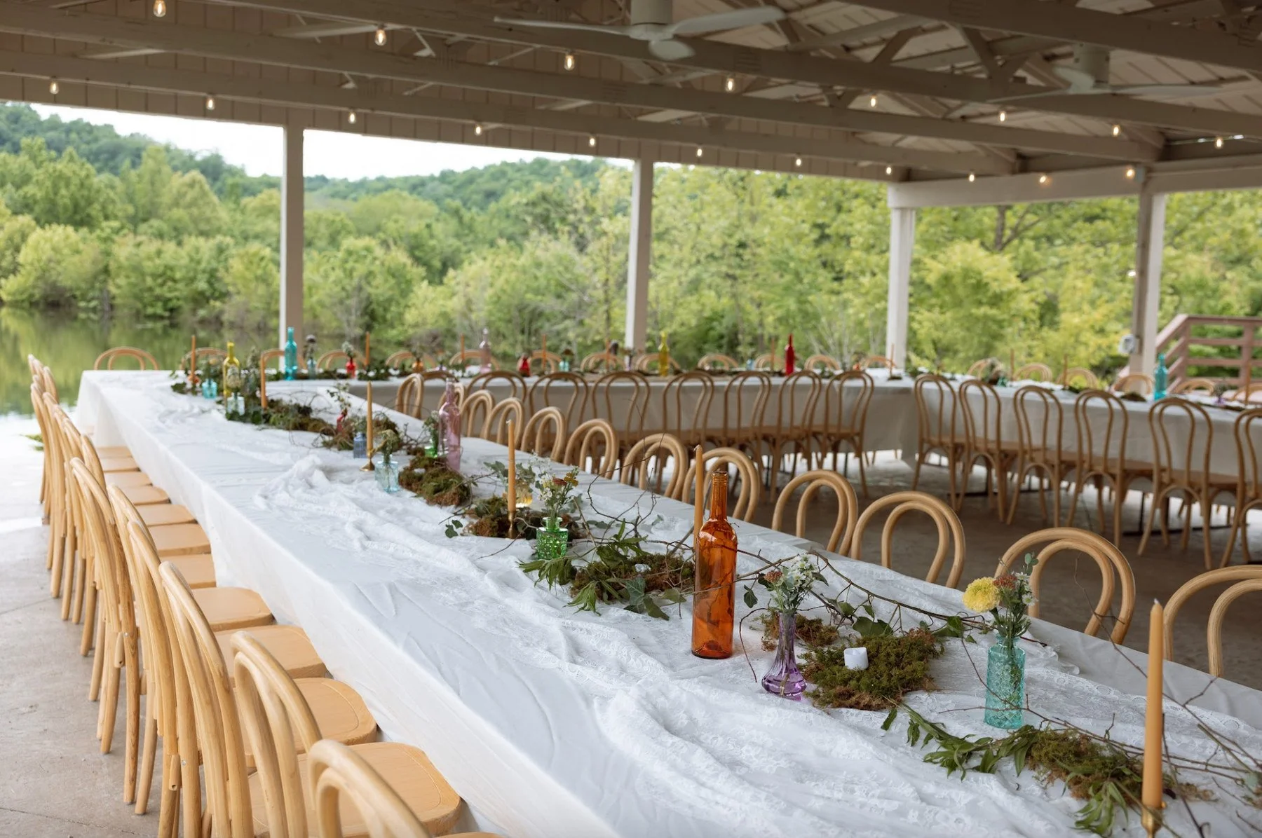 Long reception tables set beneath the open-air Pavilion overlooking the lake at The Eden Estate.