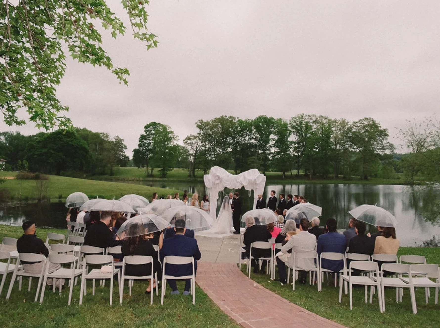 Guests gathered with umbrellas for a lakeside wedding ceremony at The Eden Estate in Ashland City, Tennessee.