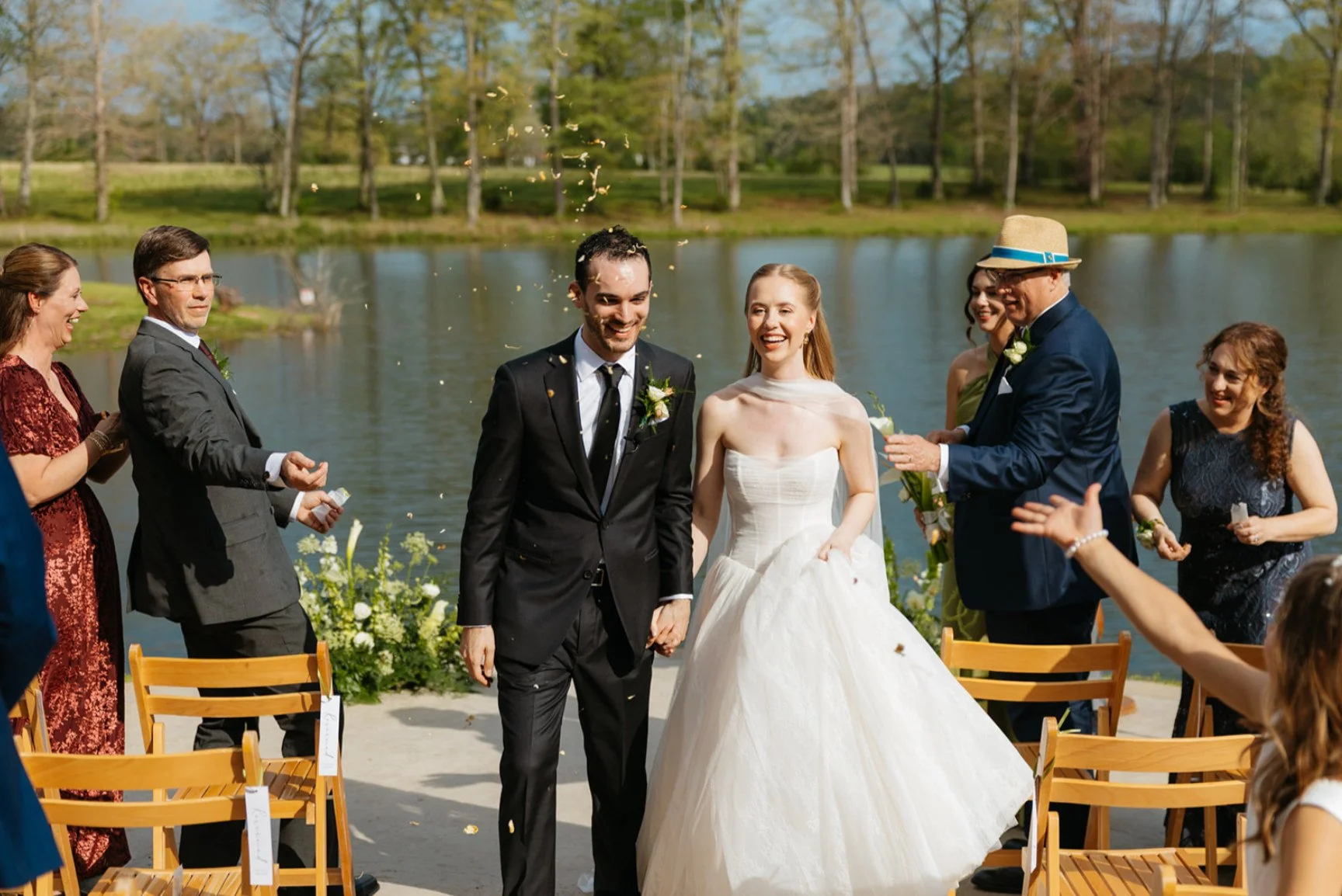 Newly married couple walking back down the aisle at a lakeside ceremony at The Eden Estate.