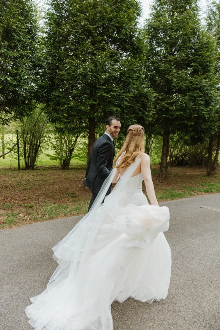 Bride and groom walking together along a tree-lined path at The Eden Estate.