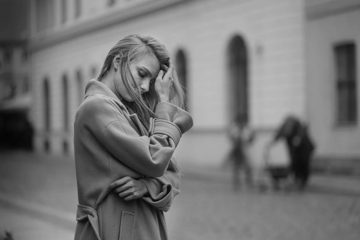 Woman walking outdoors in thoughtful reflection, navigating the difference between inner critic and intuition.