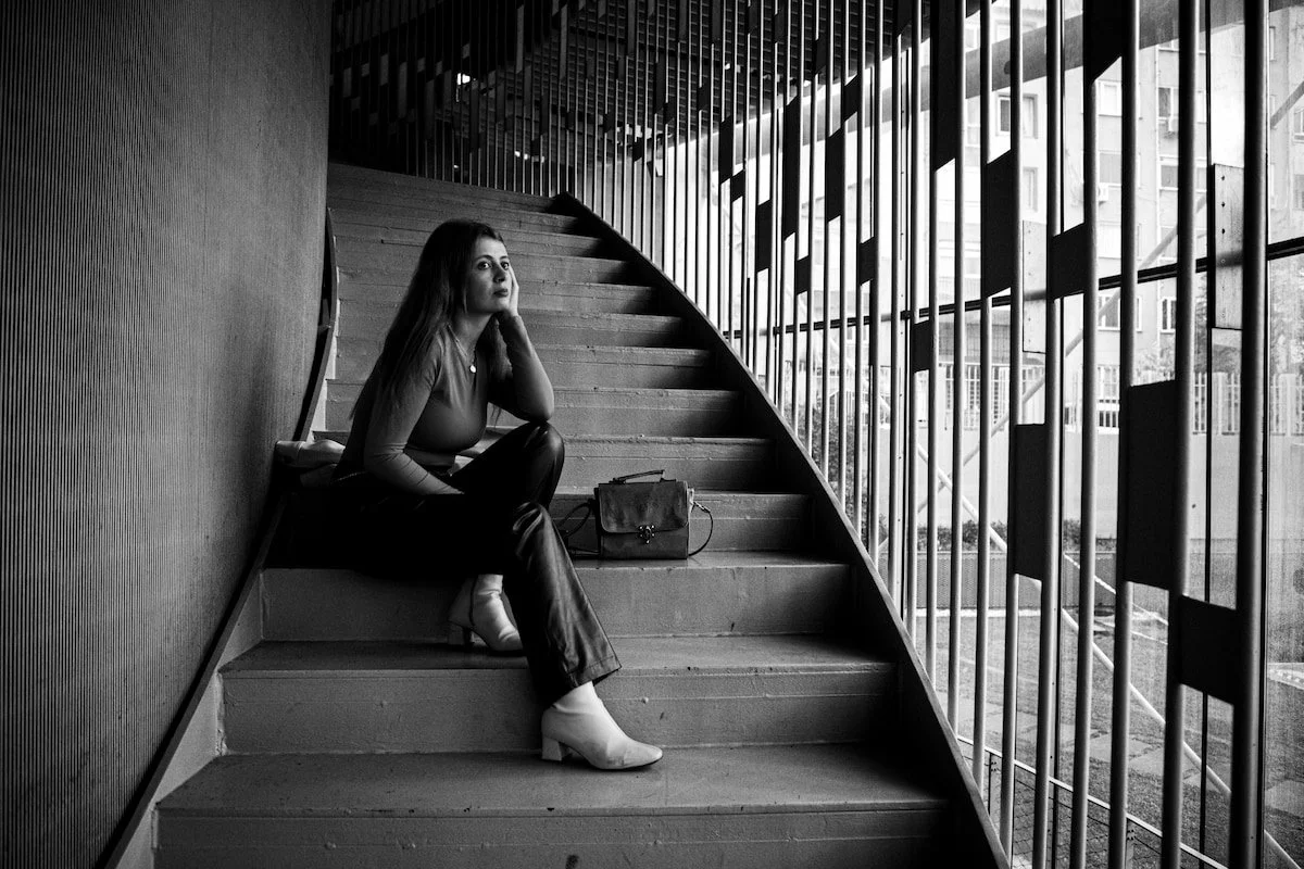 Woman sitting on a curved staircase, looking out into the distance