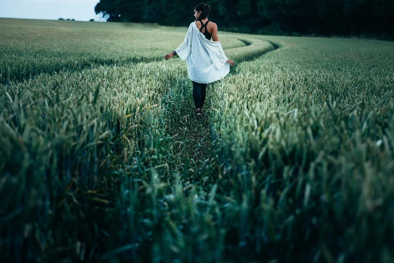 A woman walking through tall grass, symbolizing a journey of self-acceptance, mindfulness, and gentle progress in life.