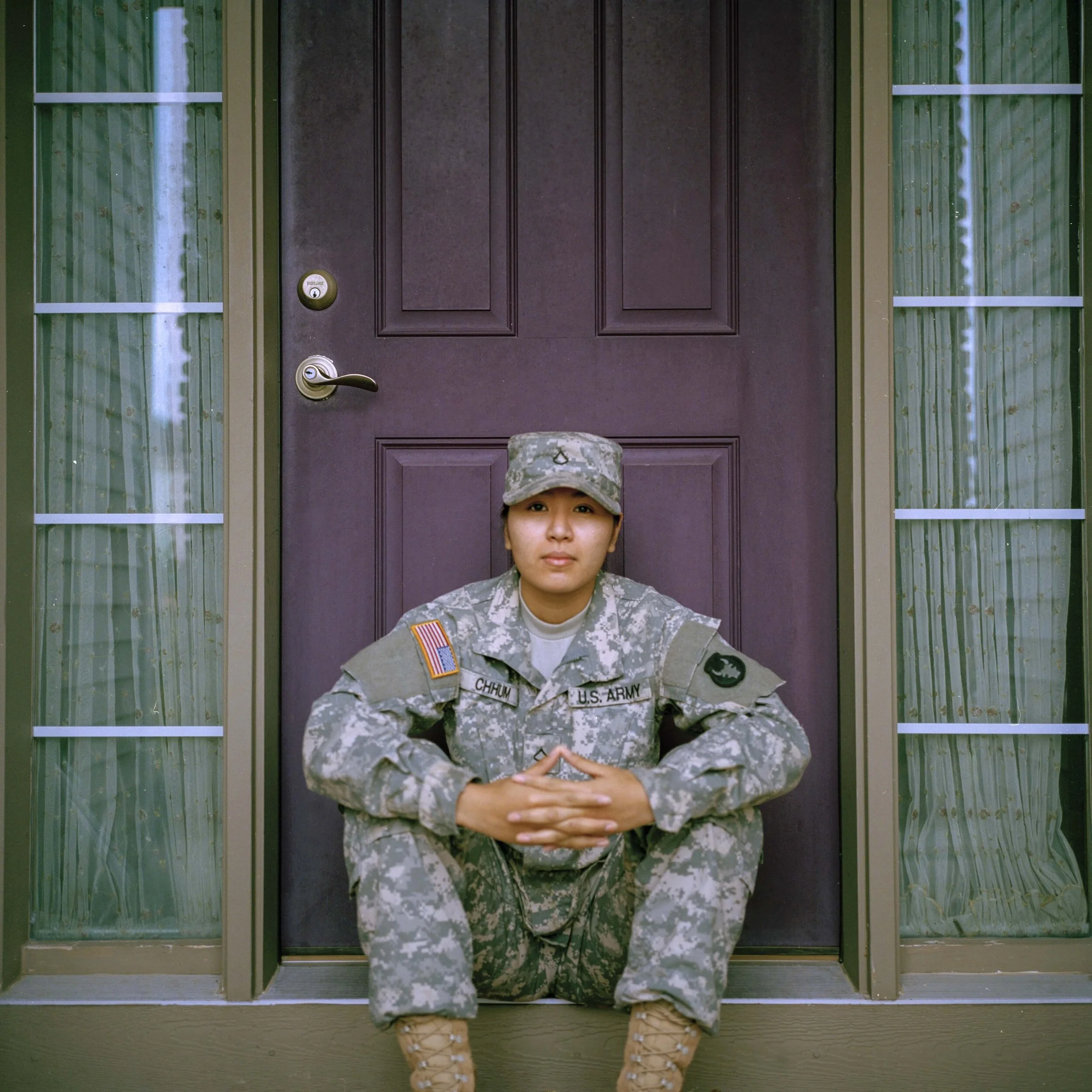 A person in military uniform sitting in front of a door.
