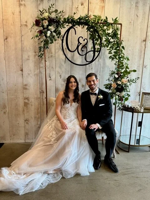 The bride, dressed in a lace top wedding gown, sits alongside her groom, who is wearing a black tuxedo, as they hold hands at Cedermont Farms Wedding Venue in Franklin, TN.