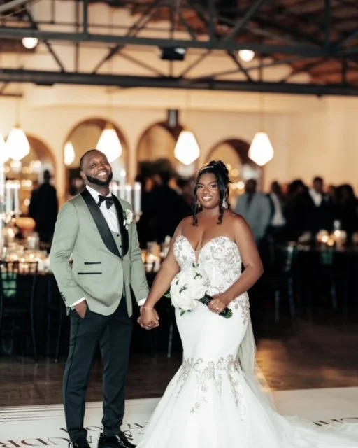 The groom wearing a tea green and black tuxedo and the bride wearing a white and green floral mermaid gown speaks to their friends and family at the wedding reception at the Saint Elle Wedding Venue in Nashville, TN.