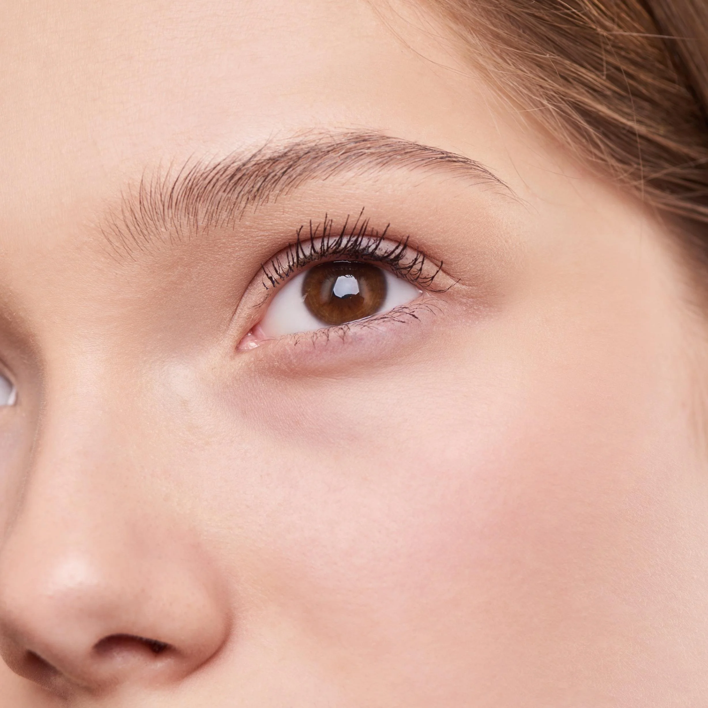 Close-up of a person's brown eye with well-groomed eyebrows and long eyelashes