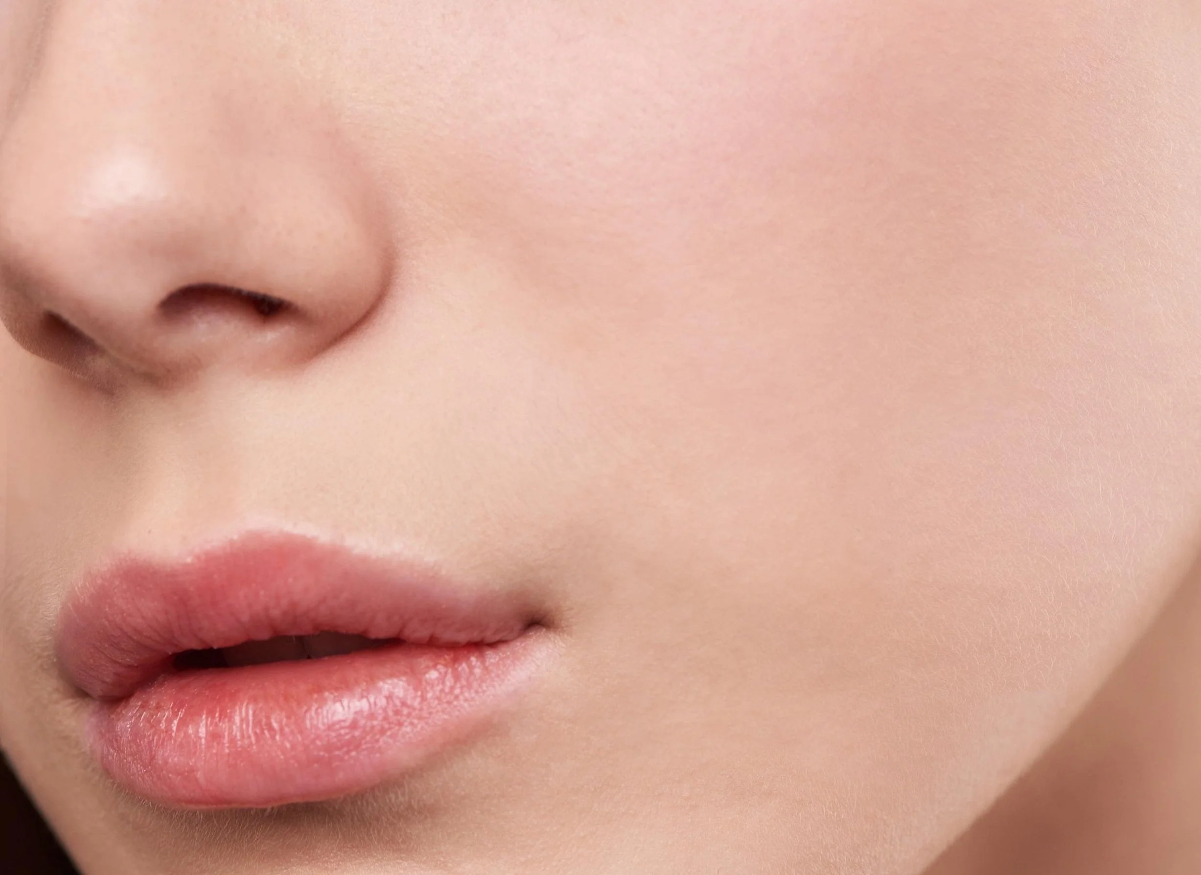 Close-up of a person's nose, lips, and a portion of cheek, with smooth skin and natural makeup.