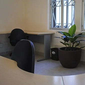 Sala de reuniones en Paseo 60, Mérida, Yucatán. Mesa de oficina con silla negra y planta en maceta junto a la ventana