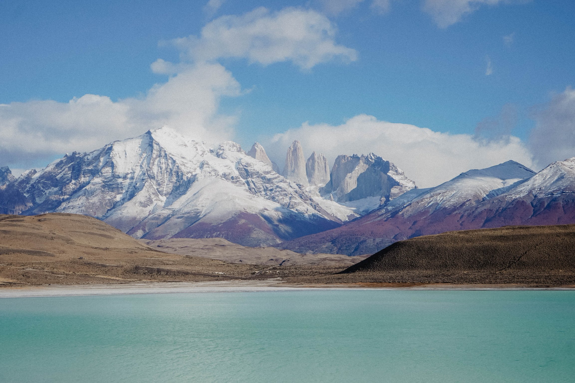 Snow-capped mountains and turquoise lake under a blue sky in Torres del Paine National Park, Chile.