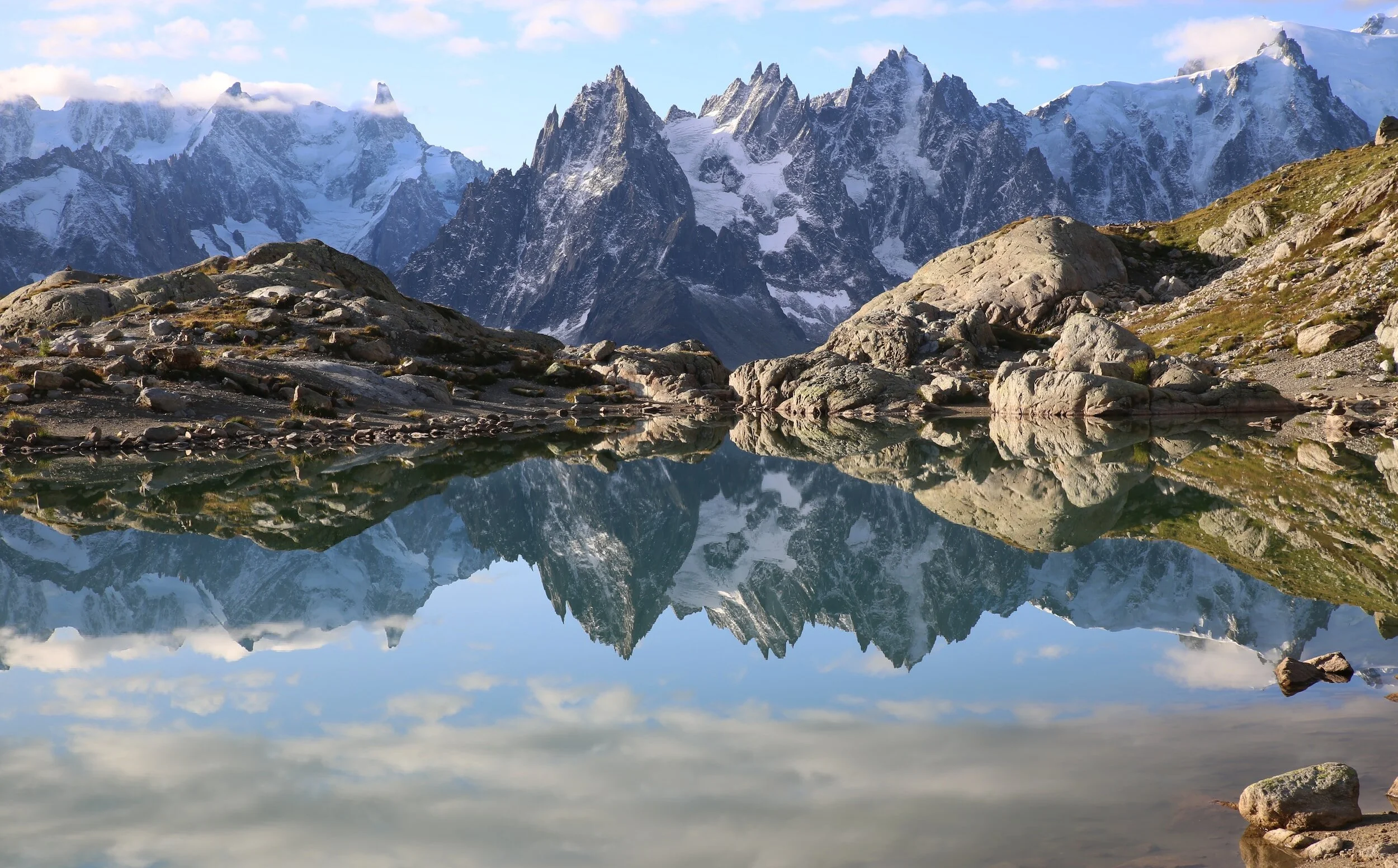 Mountain landscape with rocky peaks, snow patches, and a clear reflecting lake.