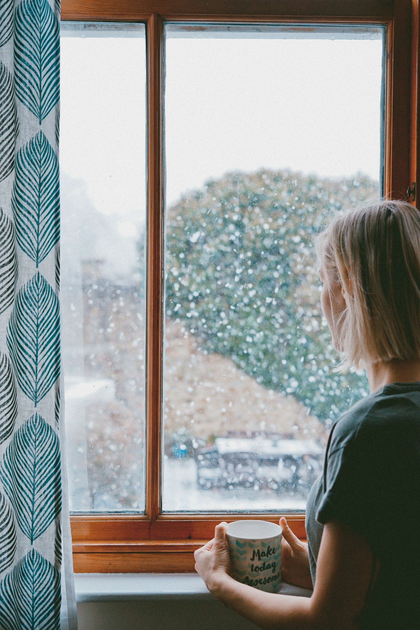 Person sitting by a window looking reflective, representing emotional processing and religious trauma healing