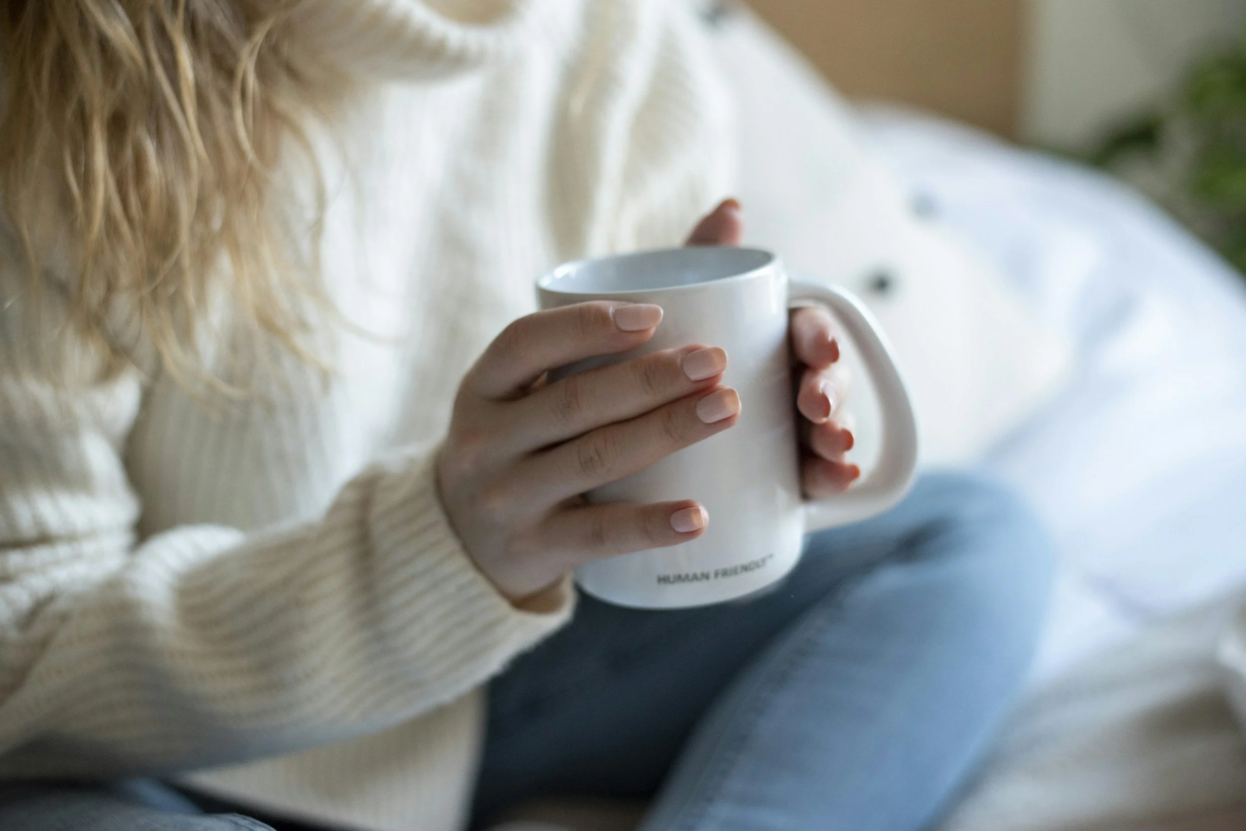 Close-up of hands holding a warm mug in a calm setting, symbolizing grounding and nervous system regulation during trauma therapy