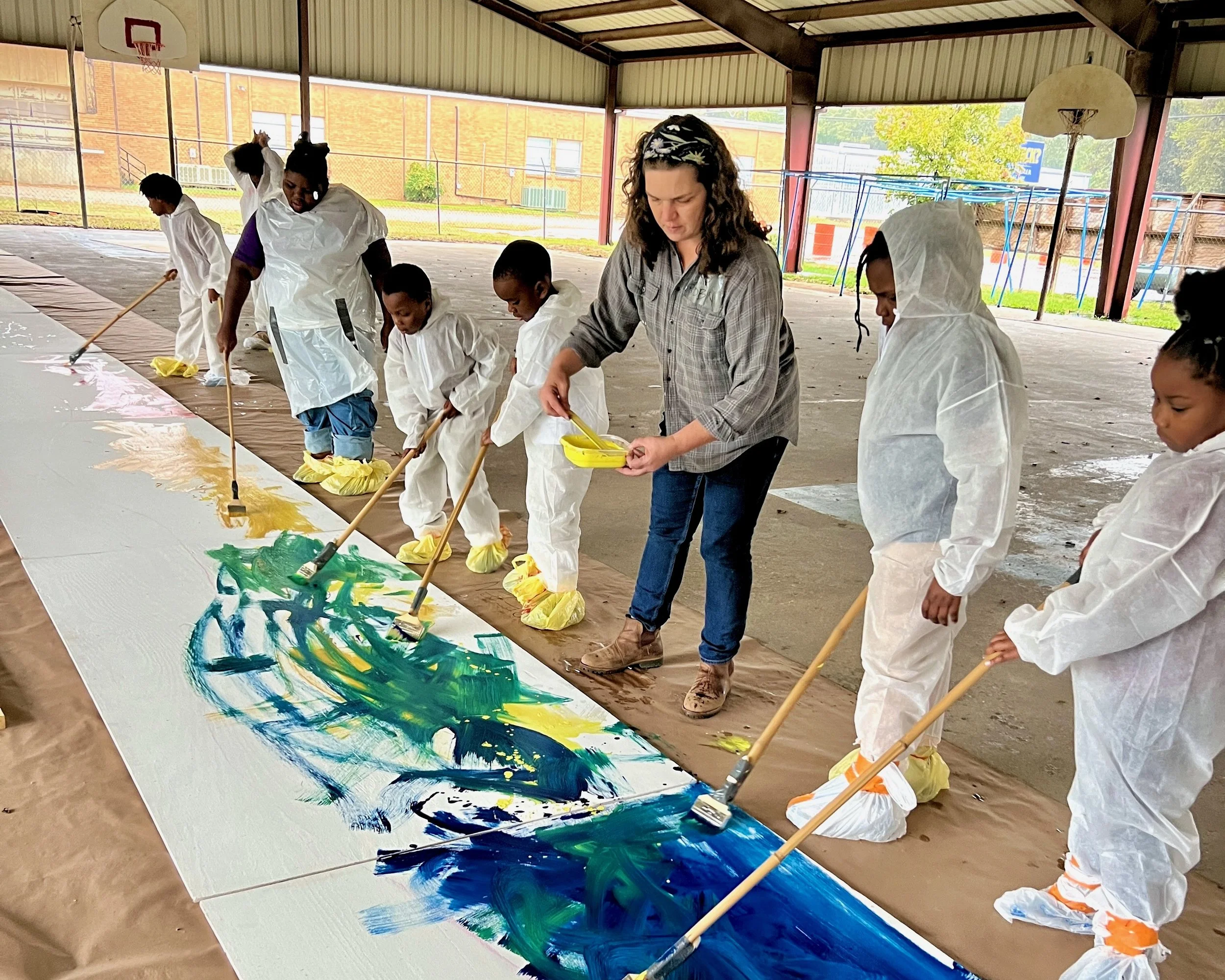 Robin leads Club members as they paint the background of the mural