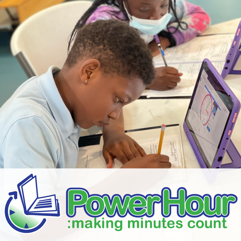 Two students working on assignments at a table, one using a tablet and the other writing in a notebook, with a logo at the bottom that says PowerHour: making minutes count.