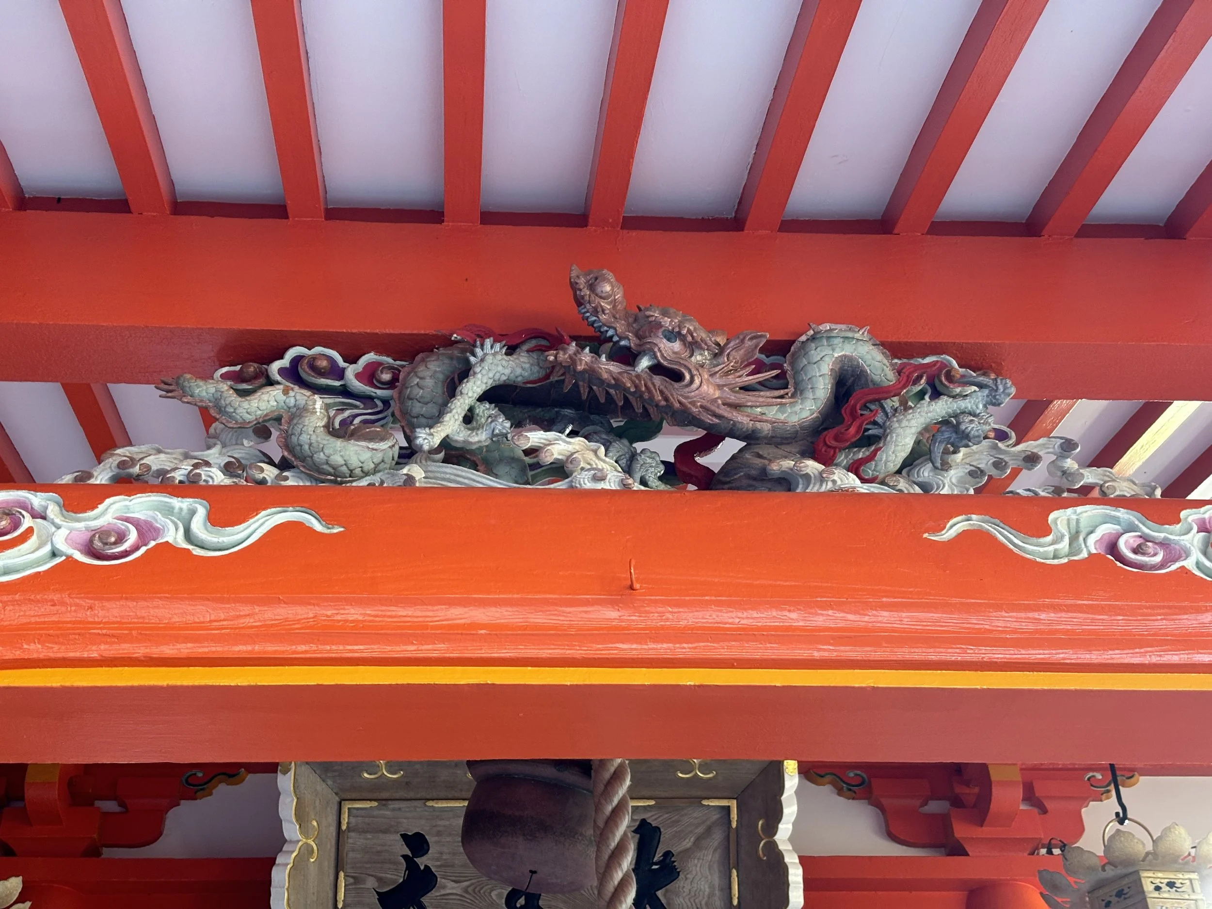 Altar with a detailed wooden dragon sculpture mounted above a red altar in a traditional Japanese shrine.