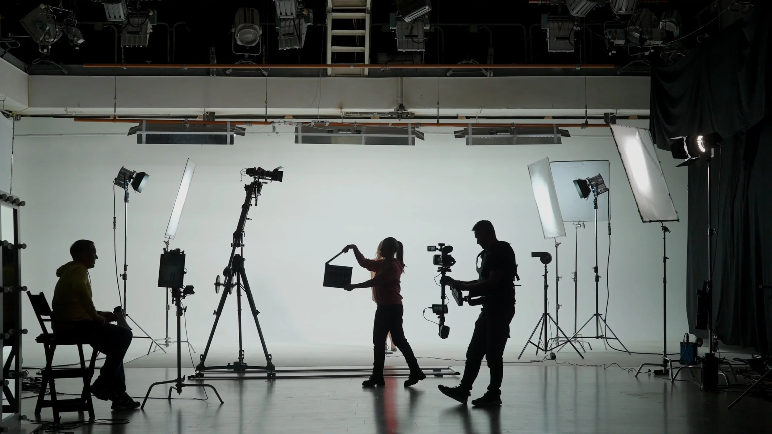 Postavitev scenske luči in upravljanje snemalne opreme med zahtevno video produkcijo v studiu.