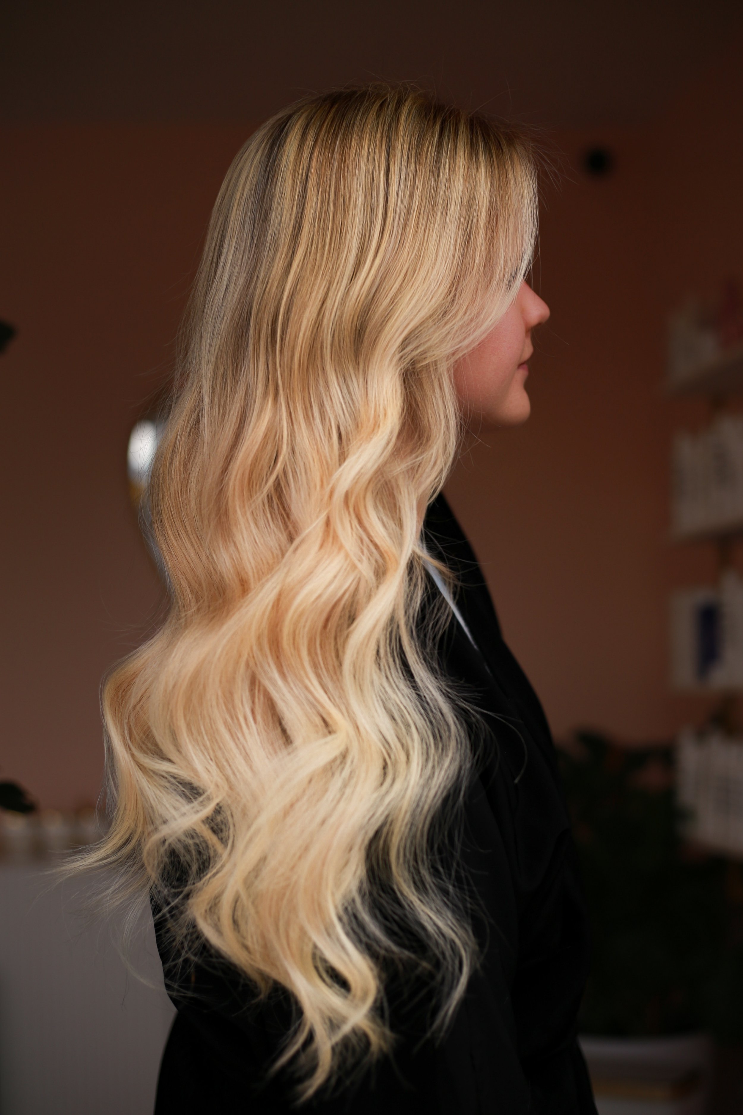 Profile of a woman with long, wavy blonde hair, wearing a black top, facing to the right.