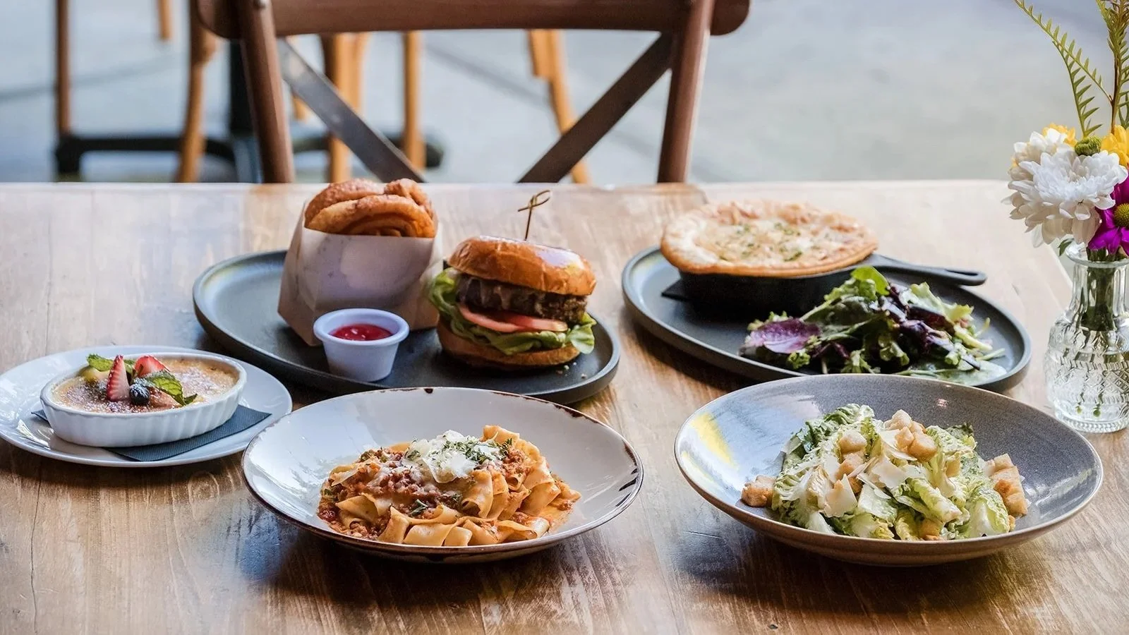 The cooperage food featuring salad, pasta, burger, chicken pot pie, creme brulee
