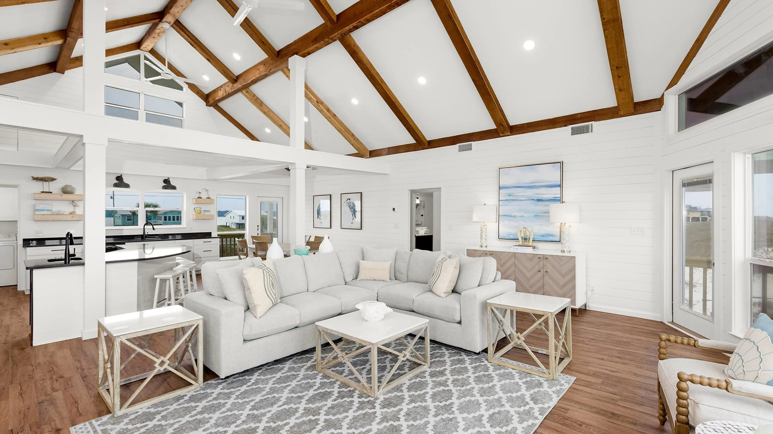 Vaulted coastal living room with exposed beams and an open kitchen beyond