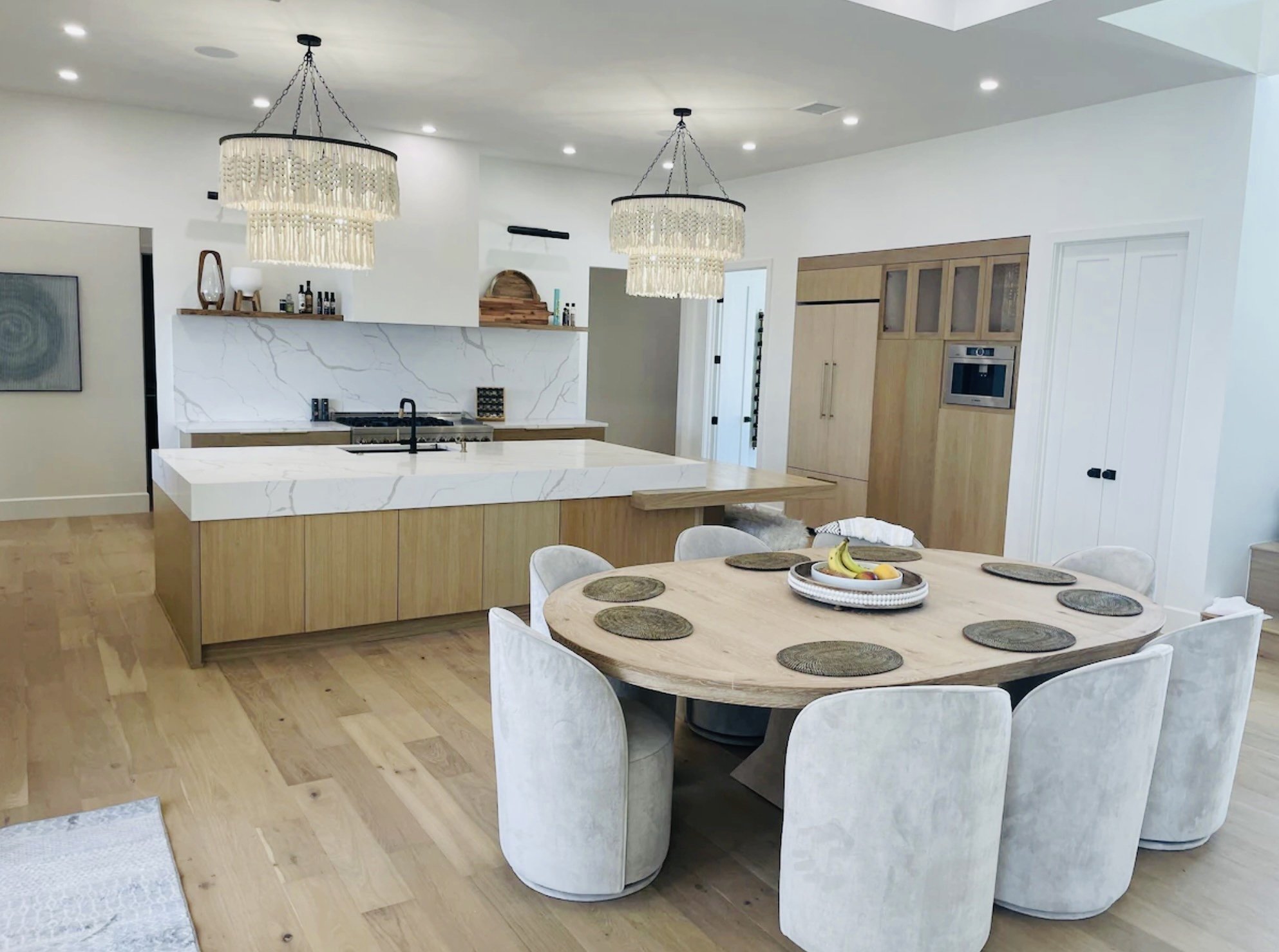 Bright kitchen and dining area with light wood cabinetry, pale flooring, and a round dining table.
