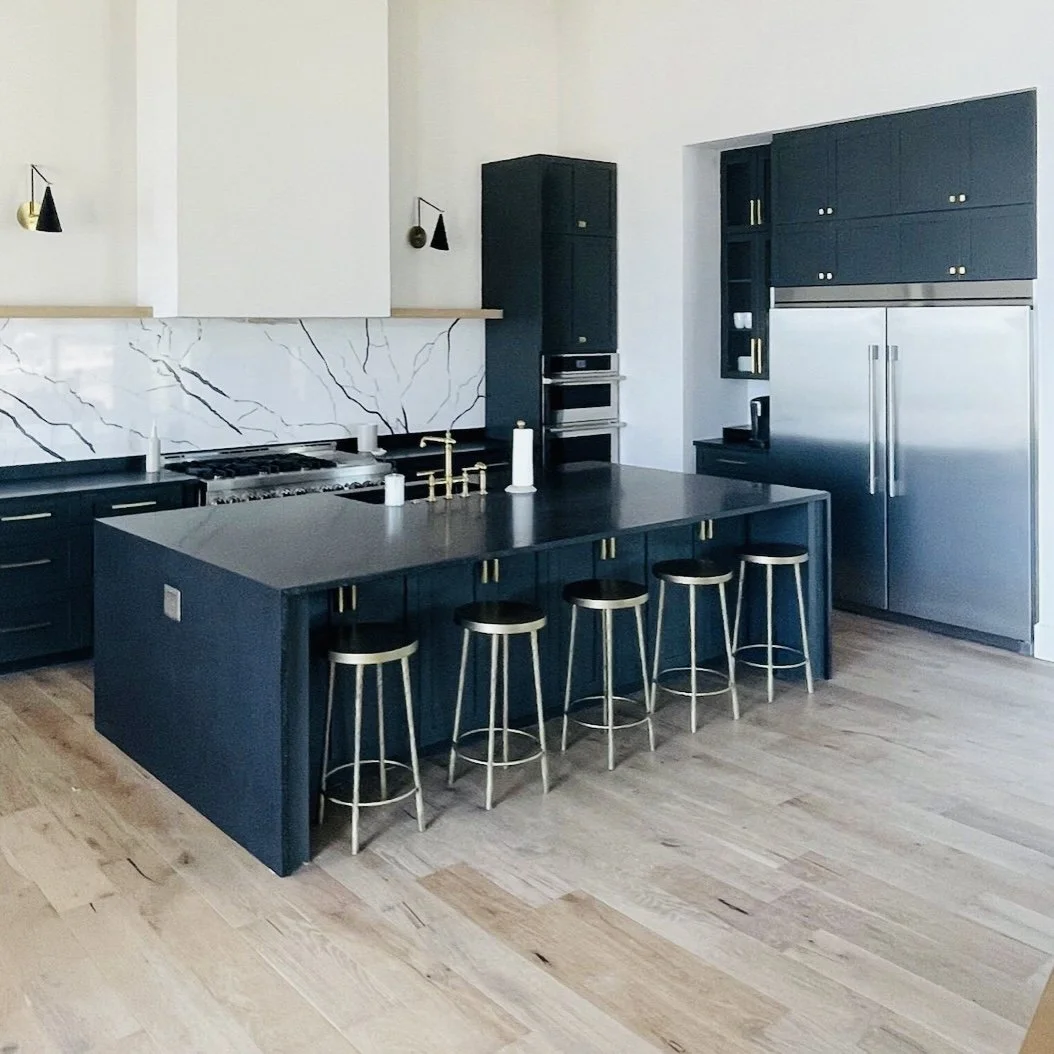 Kitchen with dark cabinetry, a large island, counter stools, and light flooring.